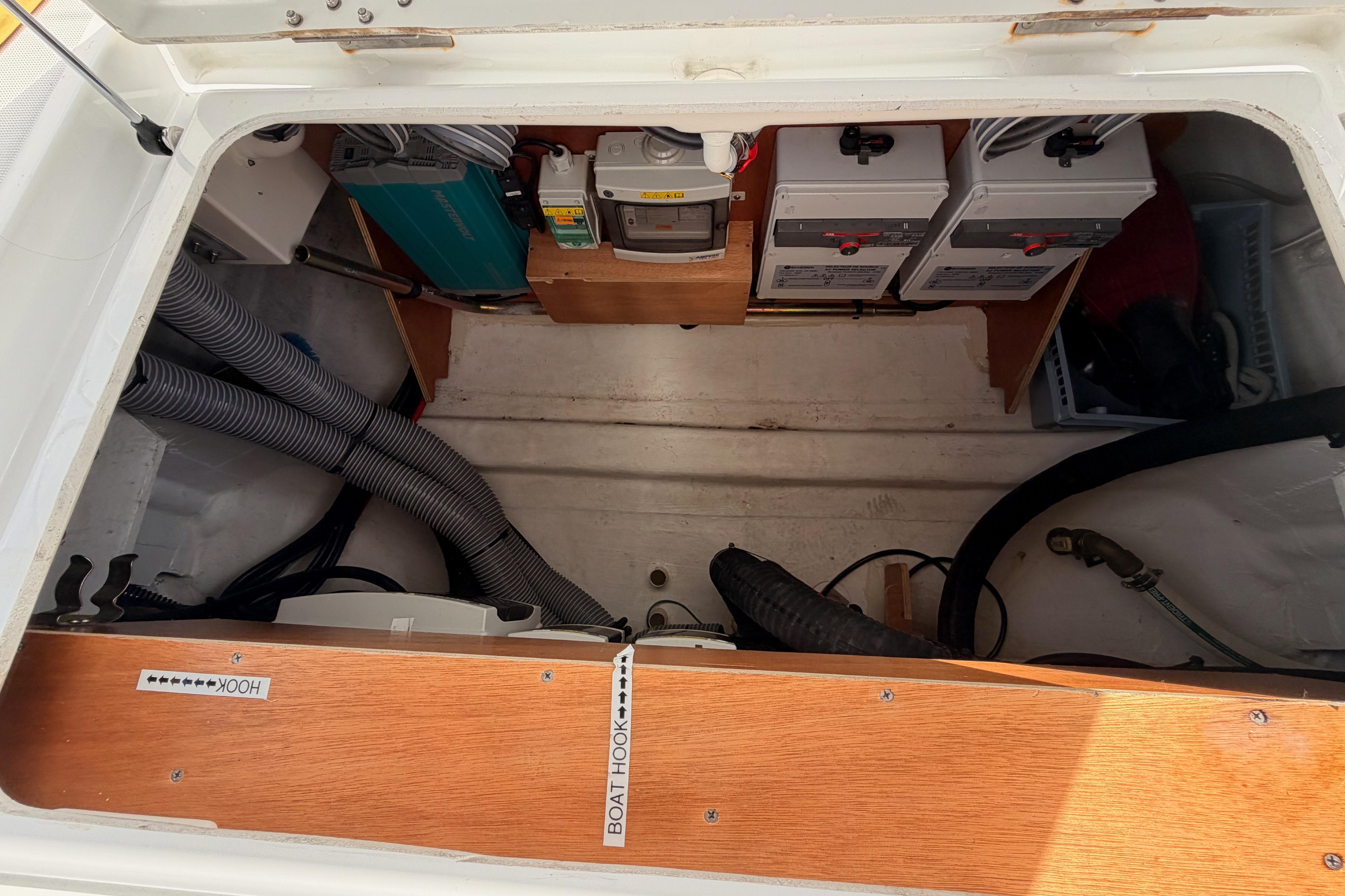 Storage compartment of a 2020 Beneteau Oceanis 46.1 sailboat, featuring electrical components and hoses.