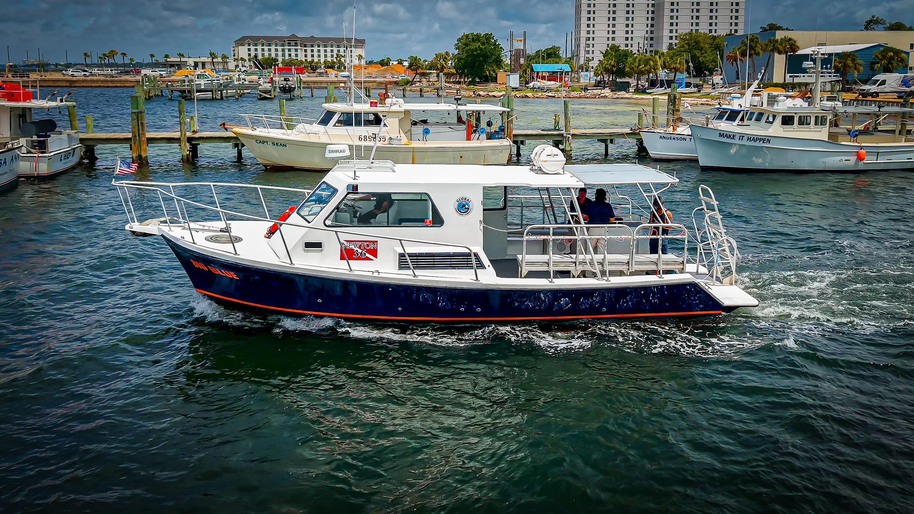A 2019 Newton 36' Dive Special boat cruising in a harbor. It features a covered deck.