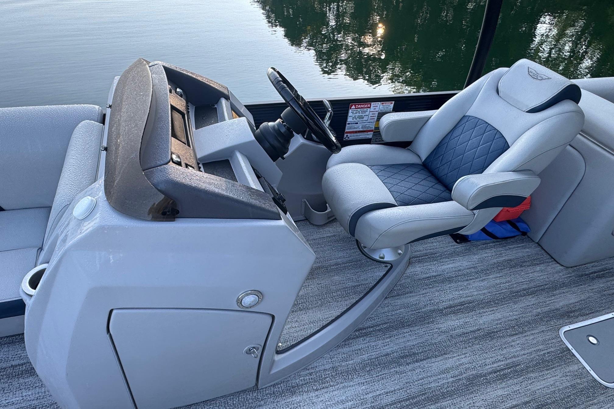 2025 Bennington 26 L Top Deck boat interior with steering console and cushioned captain's chair.