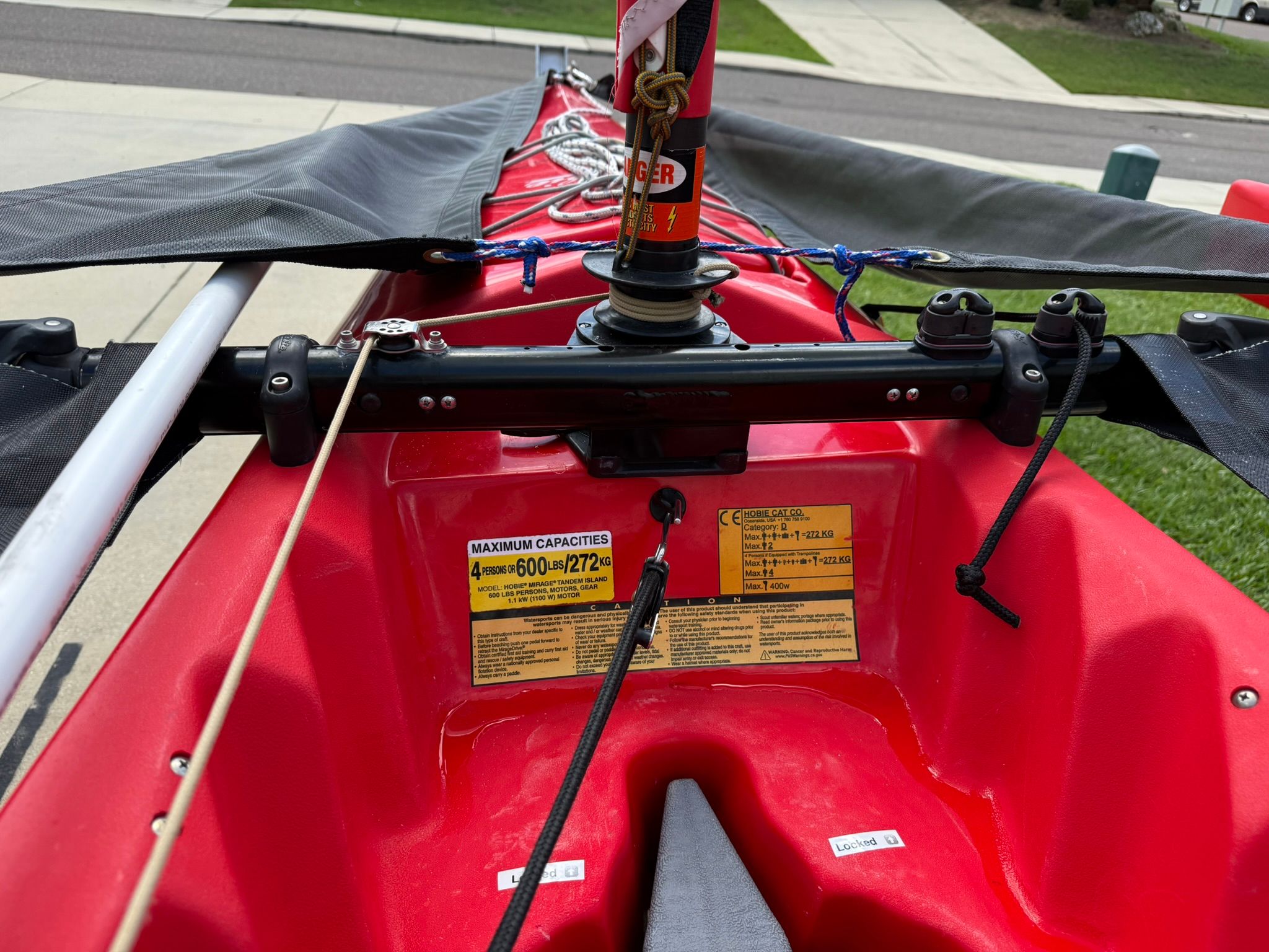 Close-up of a Hobie Mirage Tandem Island kayak cockpit with sail and controls.