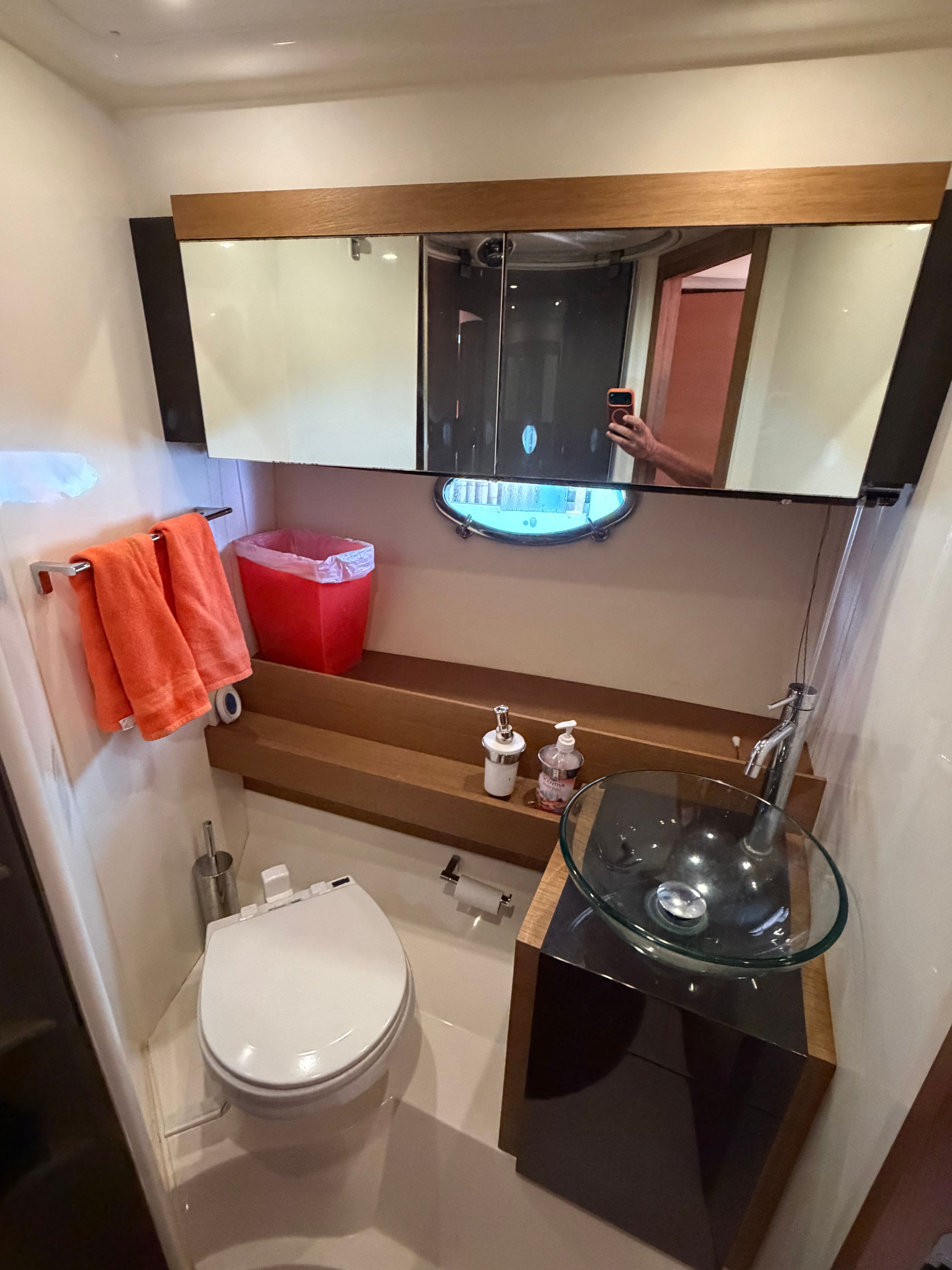 The image shows a modern yacht bathroom with a sink, toilet, and mirror.