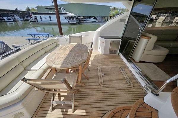 Sunseeker Manhattan 66 yacht deck with wooden table and seating, docked at marina.