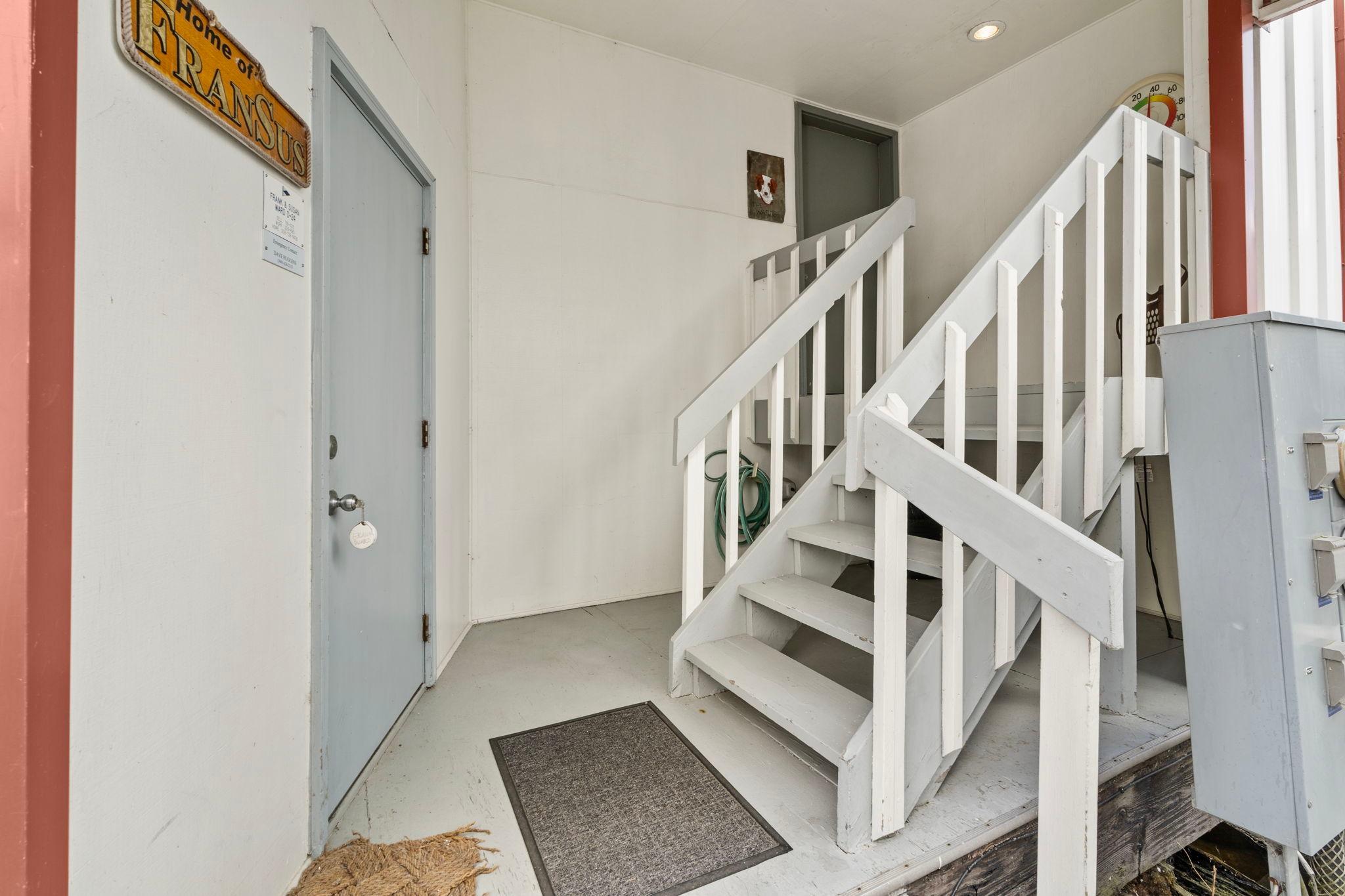 Entrance of a 1976 custom boathouse with white stairs and a gray door.