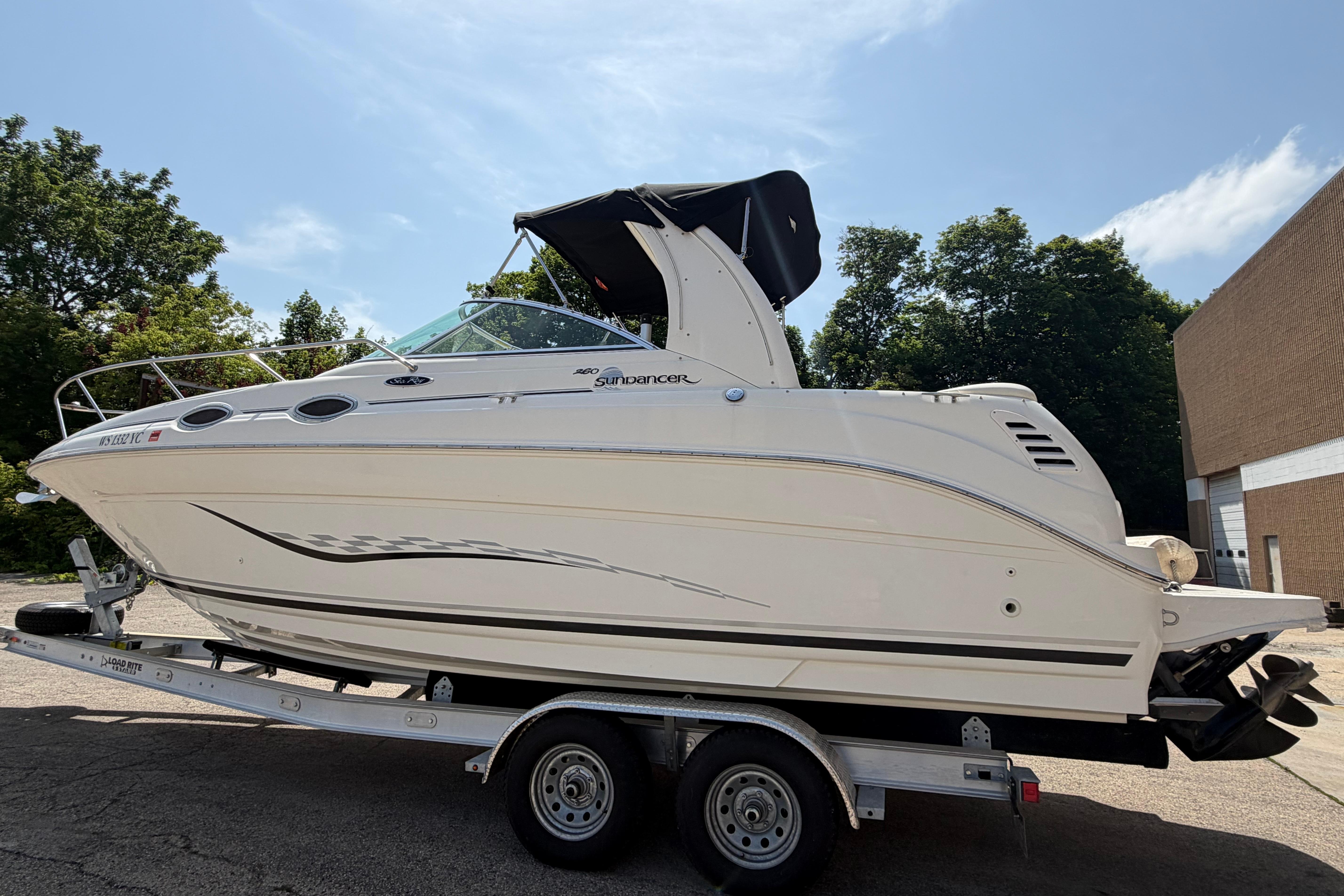 2004 Sea Ray Sundancer 260 boat on trailer, parked outdoors under clear sky.