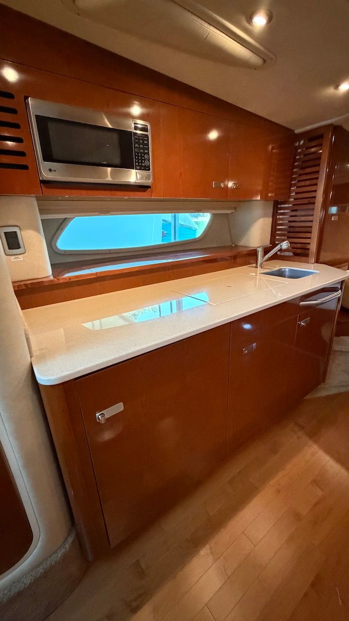 The galley of a 2011 Sea Ray Sundancer 370 with wooden cabinets and a window.