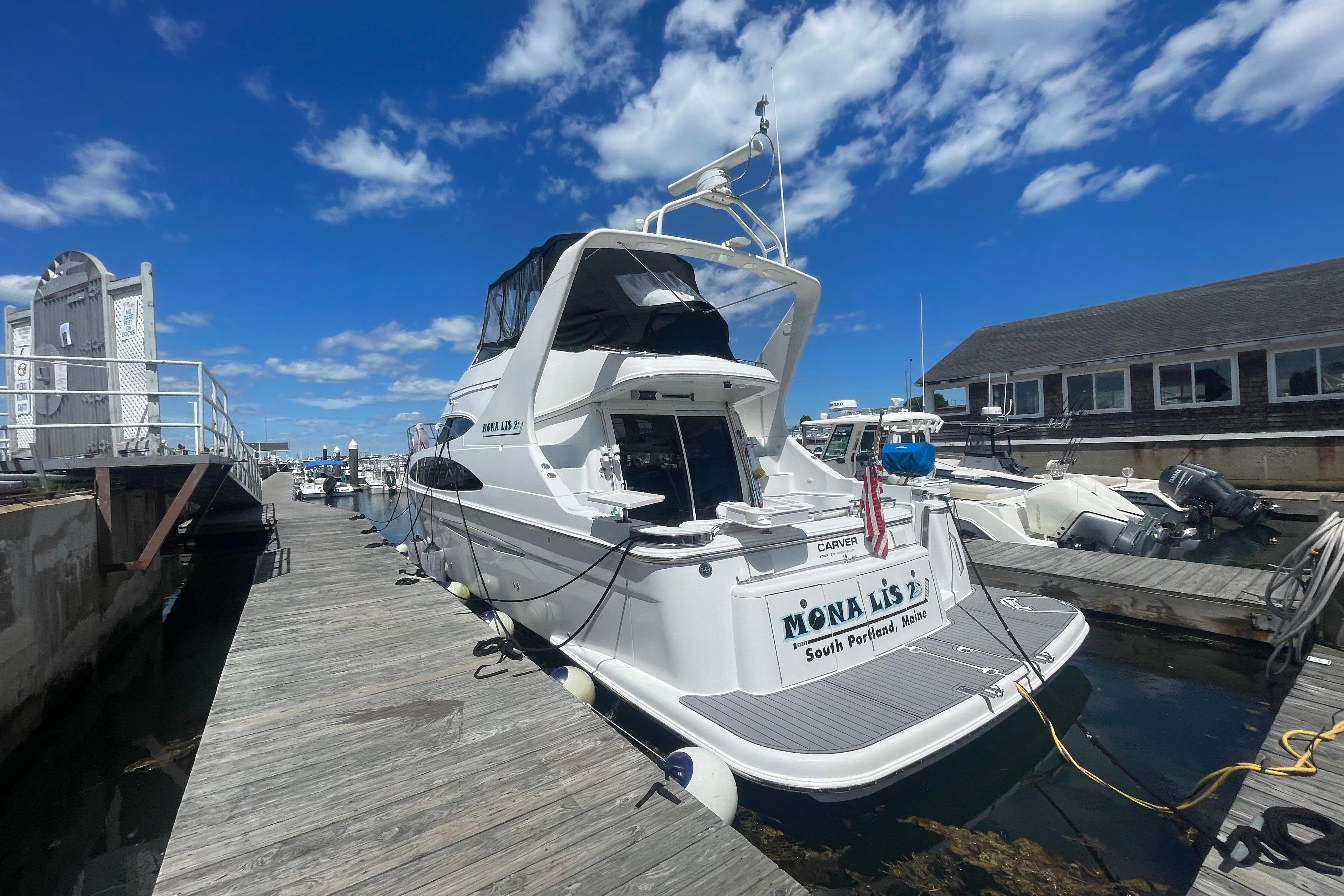 2002 Carver 410 Sport Sedan docked at marina under clear blue sky.