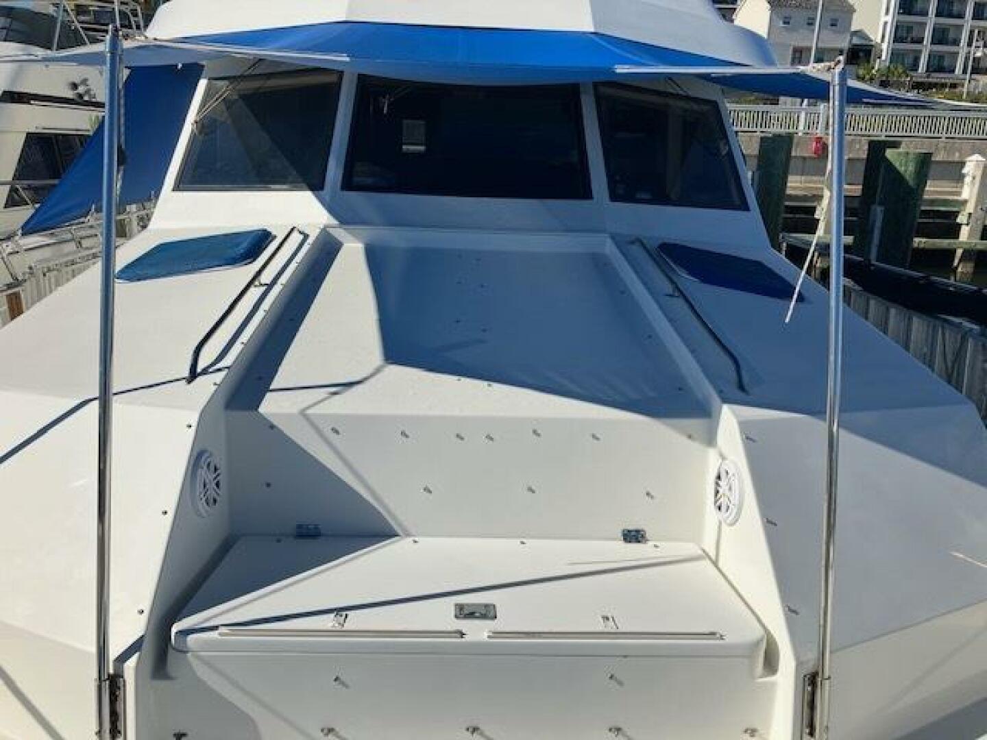 1996 Hatteras 70 Sport Deck Motor Yacht with blue canopy, docked at marina.
