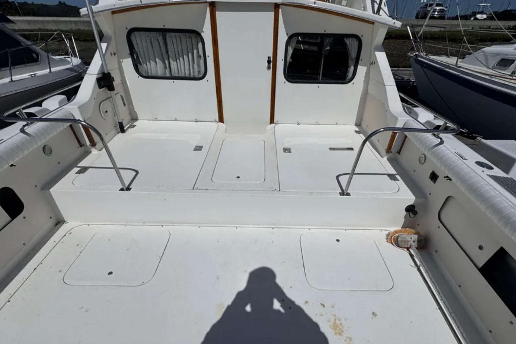 1988 Bertram 28 Sport Fisherman boat deck, spacious and well-maintained, with white seating and railings.