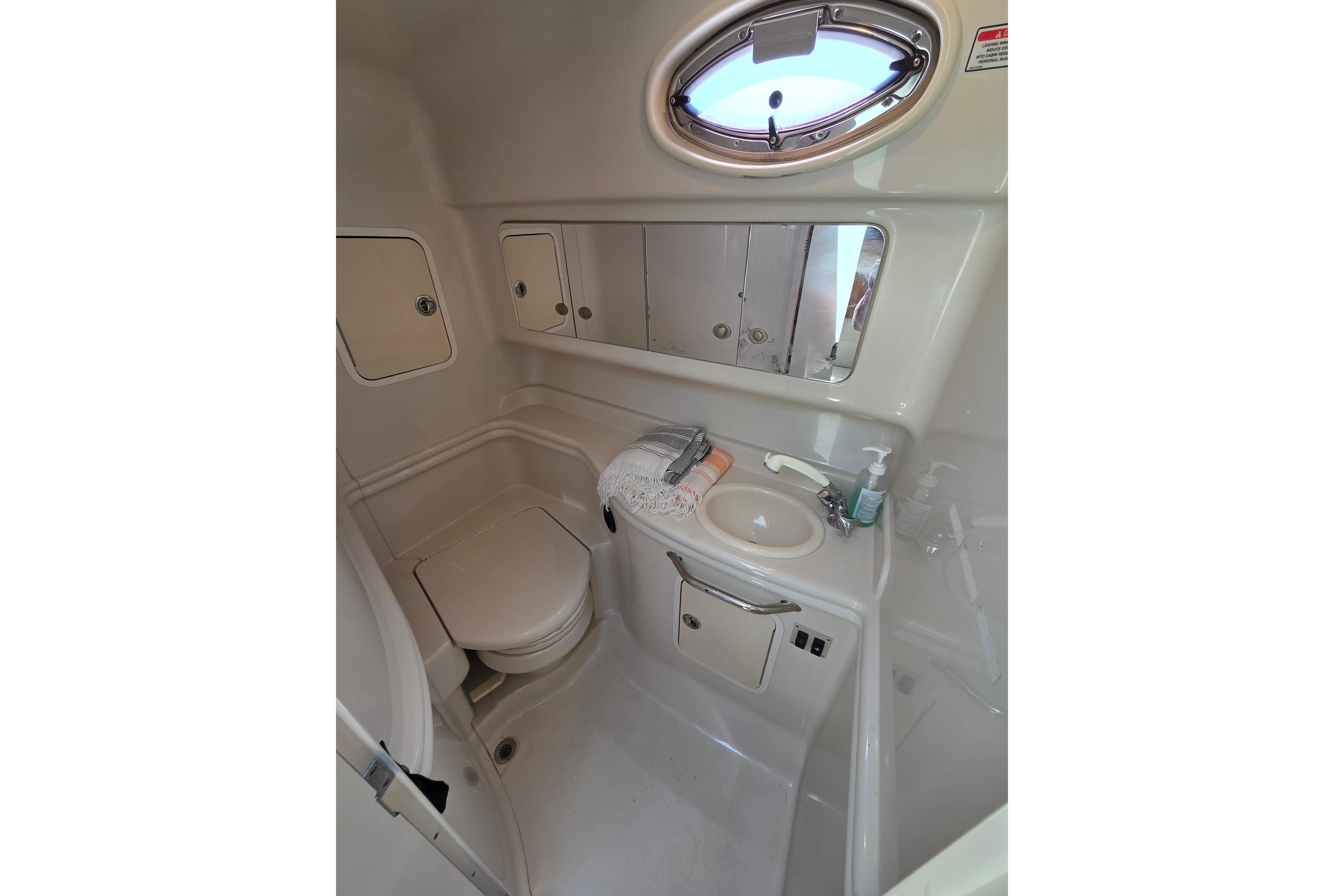 2006 Sea Ray Sundancer 320 bathroom with toilet, sink, mirror, and storage cabinets.