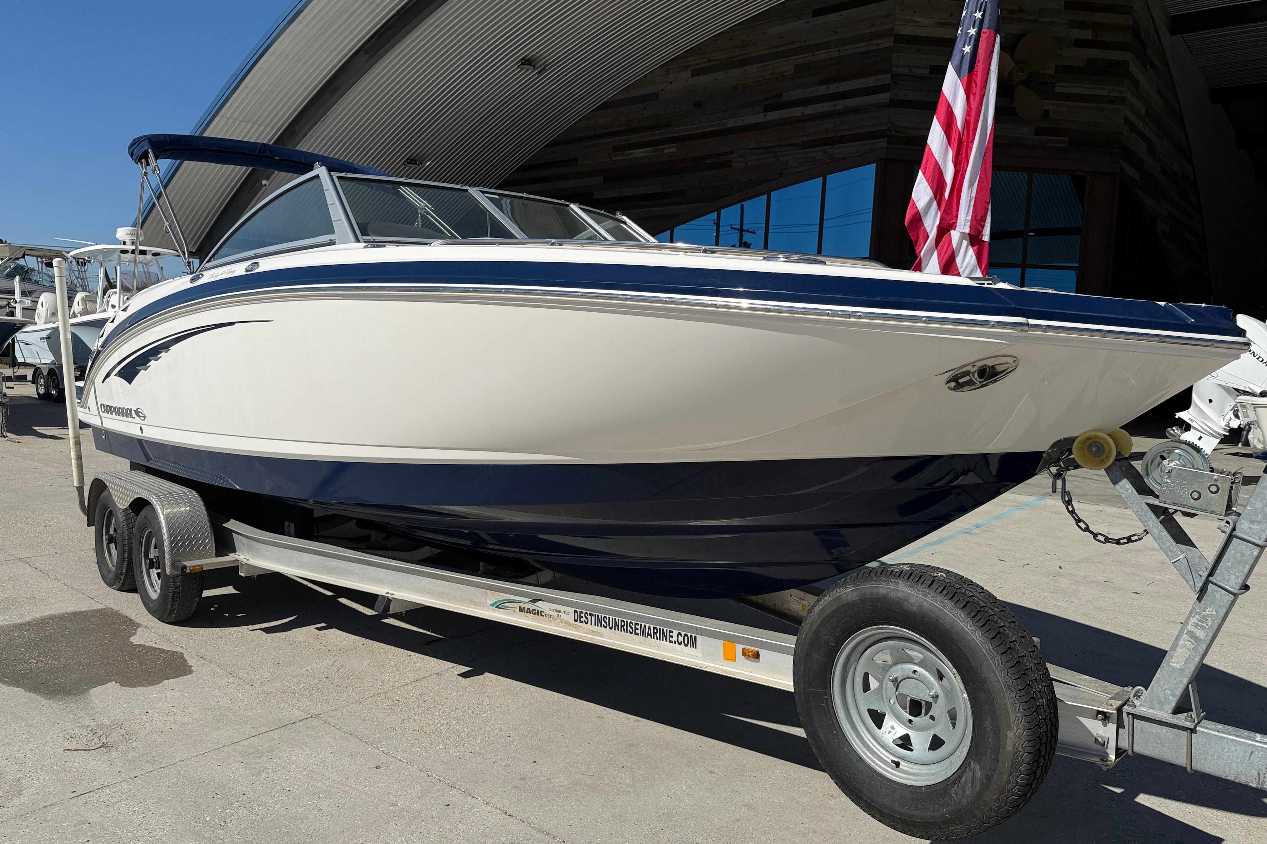 2014 Chaparral 264 Sunesta boat on trailer with American flag, parked outdoors.