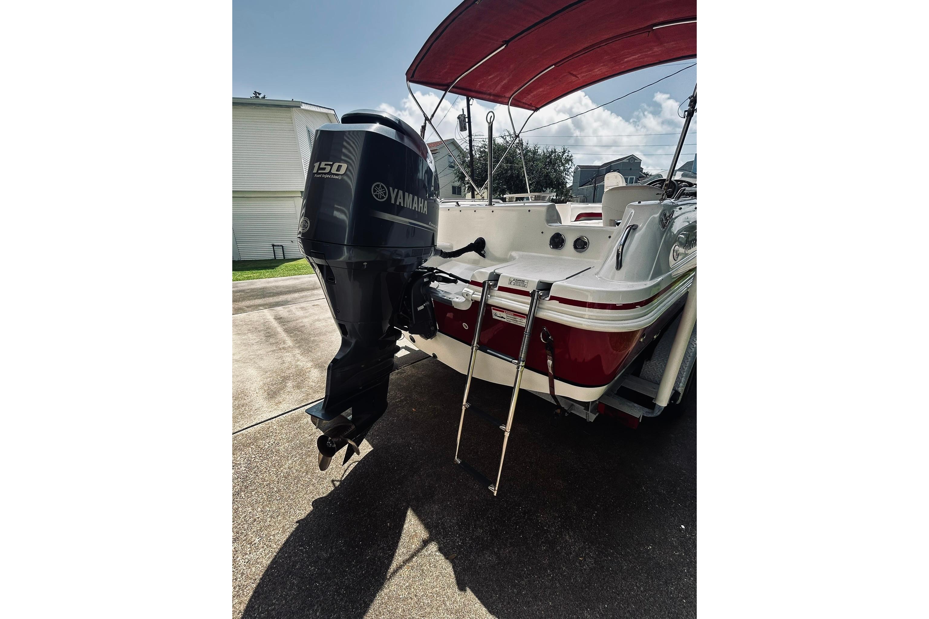 2013 Hurricane SunDeck Sport 201 OB boat with Yamaha 150 engine and red canopy.