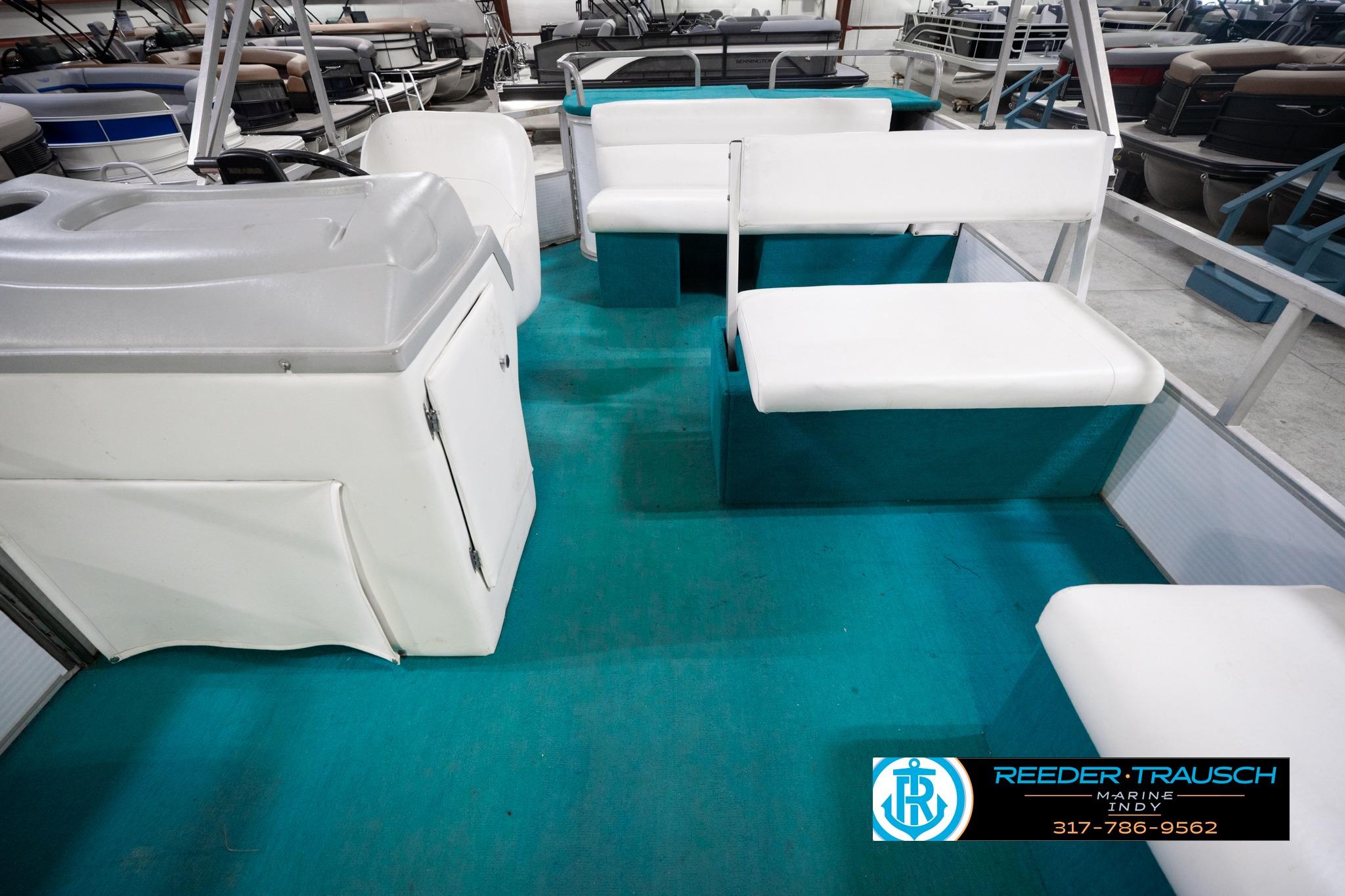 Interior of a 1992 Godfrey Sweetwater boat with white seating and teal flooring.