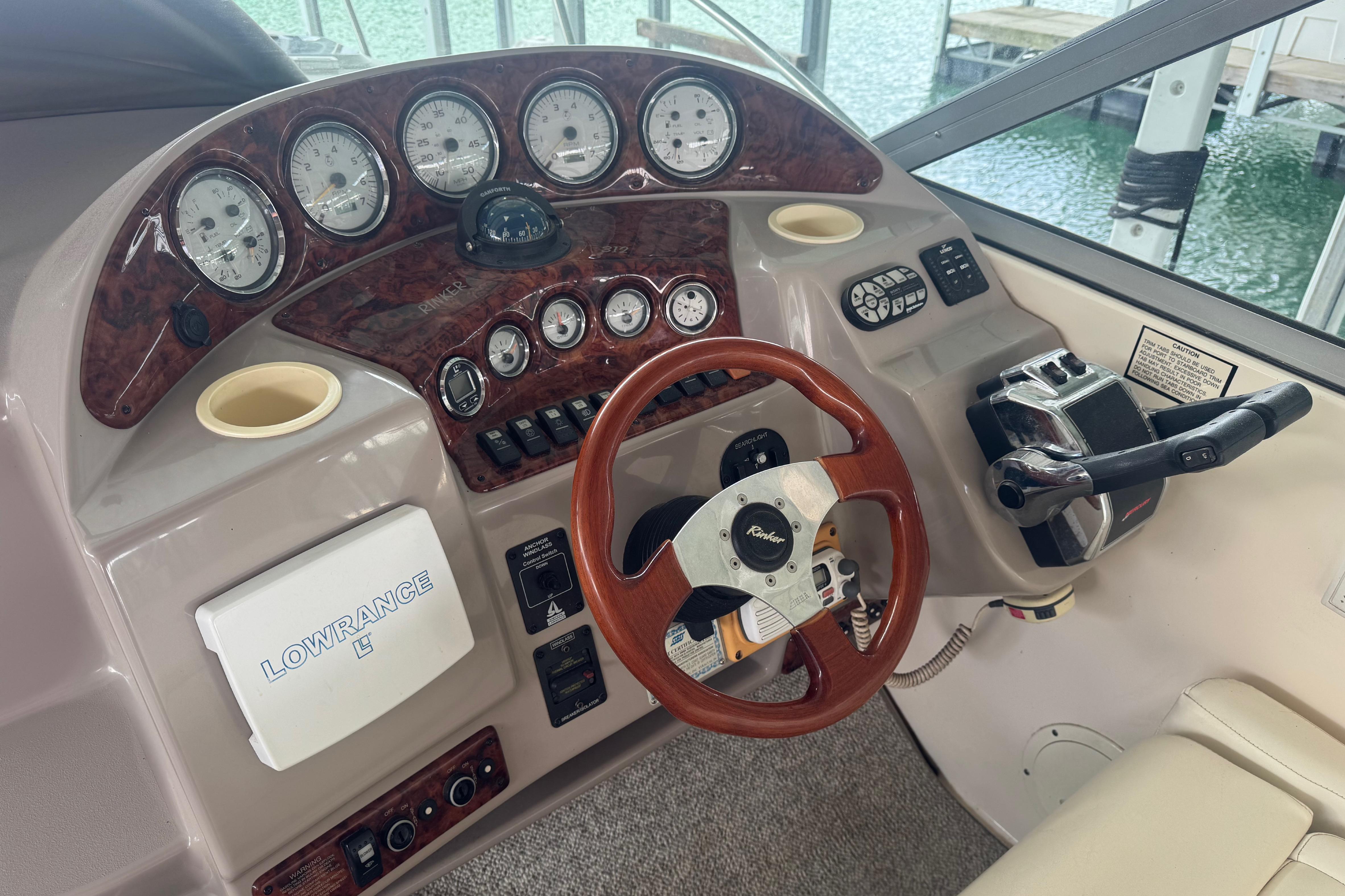 2004 Rinker Fiesta Vee 312 boat dashboard with gauges, steering wheel, and Lowrance system.