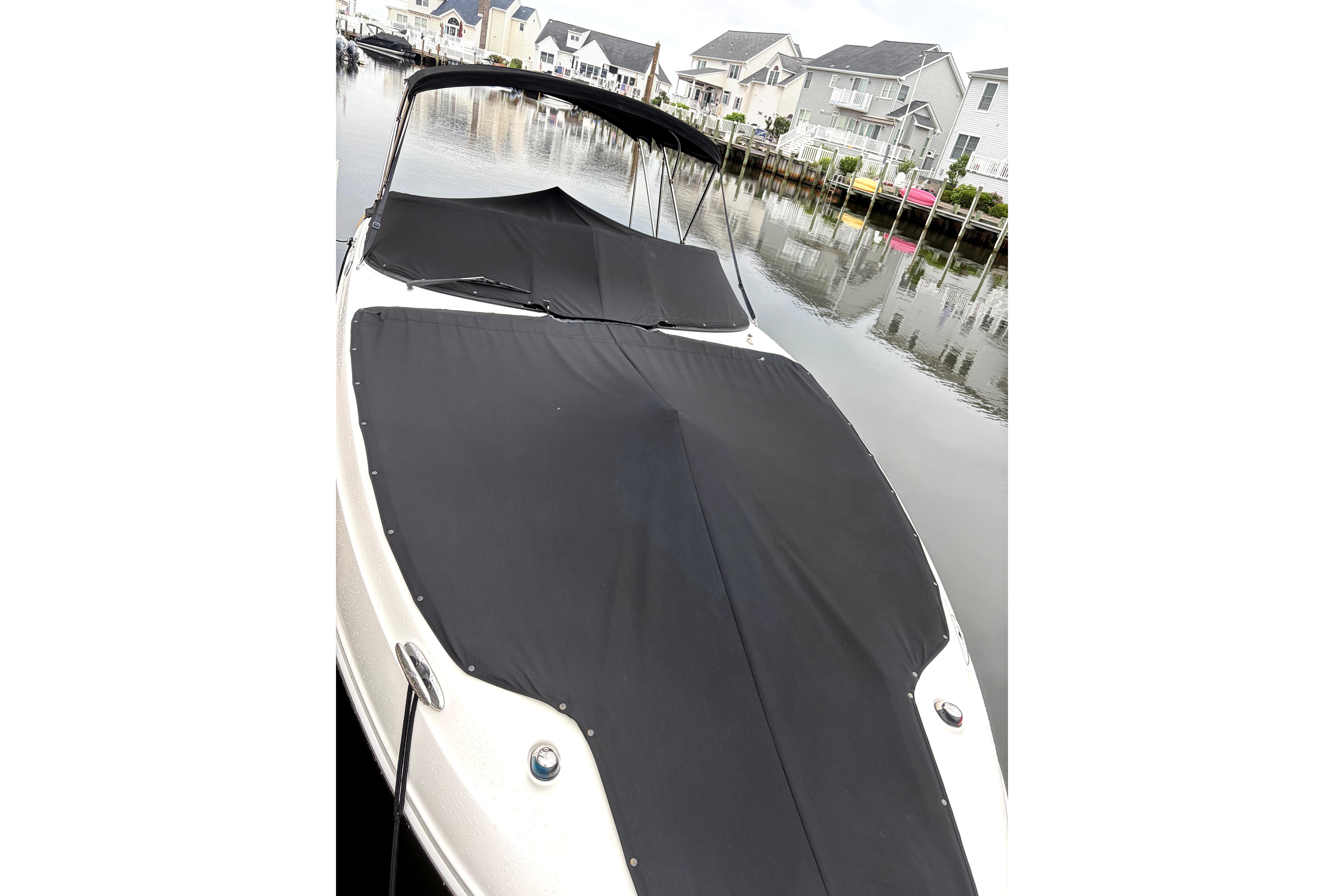 2014 Sea Ray 260 Sundeck boat with black cover, docked near waterfront homes.