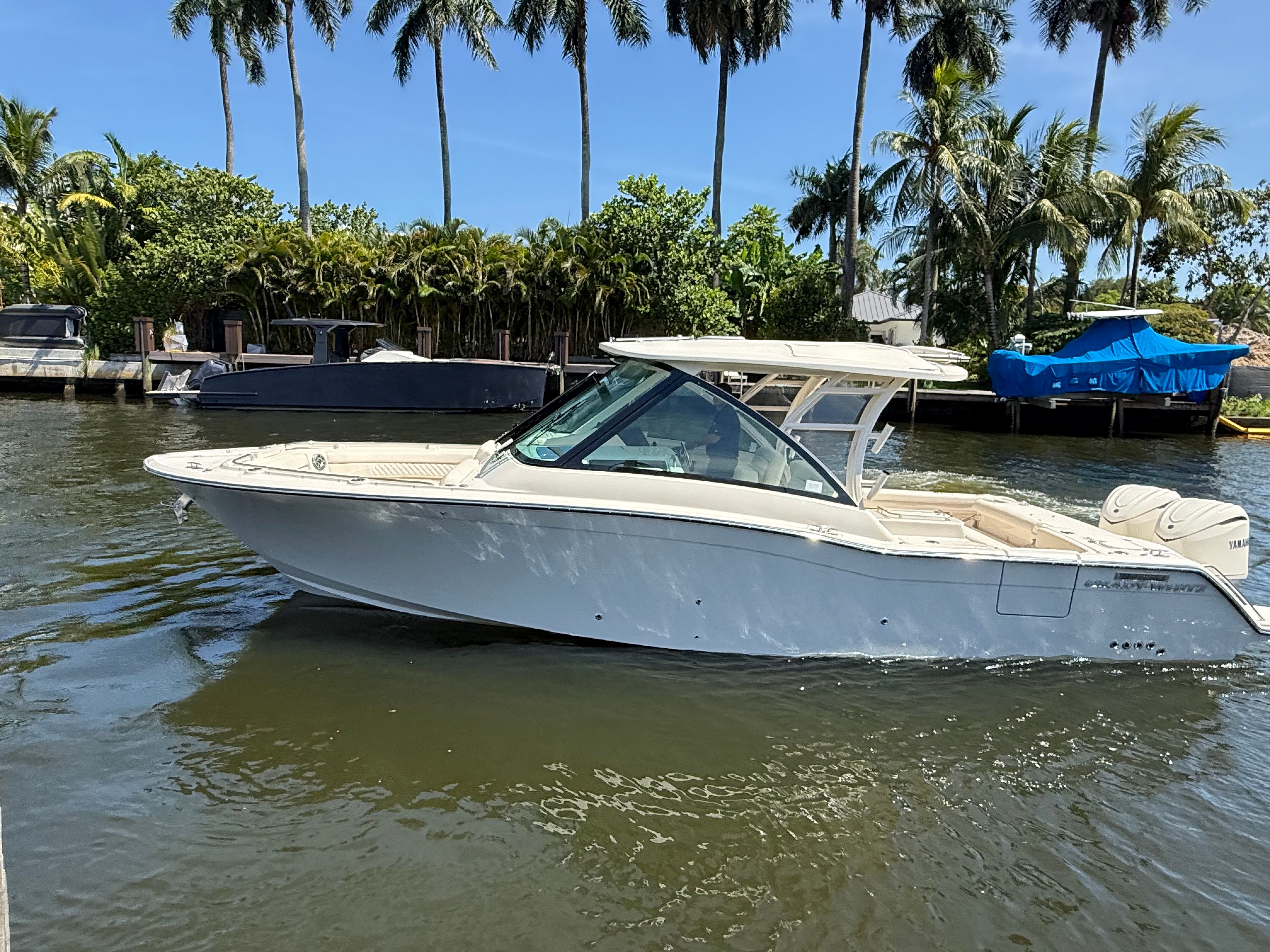 A 2027 Grady-White Freedom 325 boat on calm water, surrounded by palm trees.