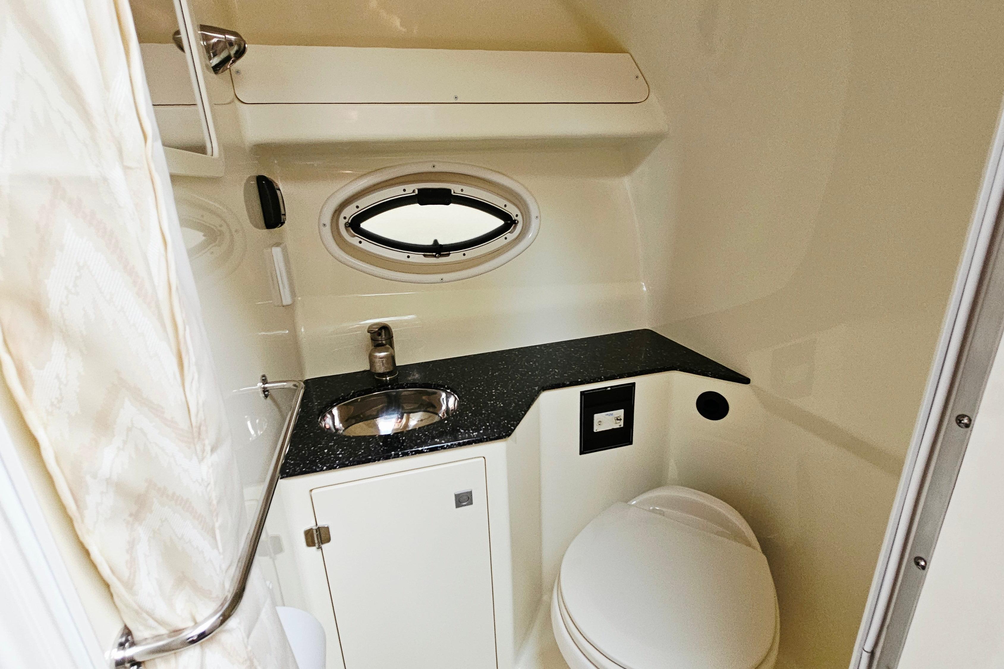 2016 Monterey 295 Sport Yacht bathroom with sink, toilet, and porthole window.