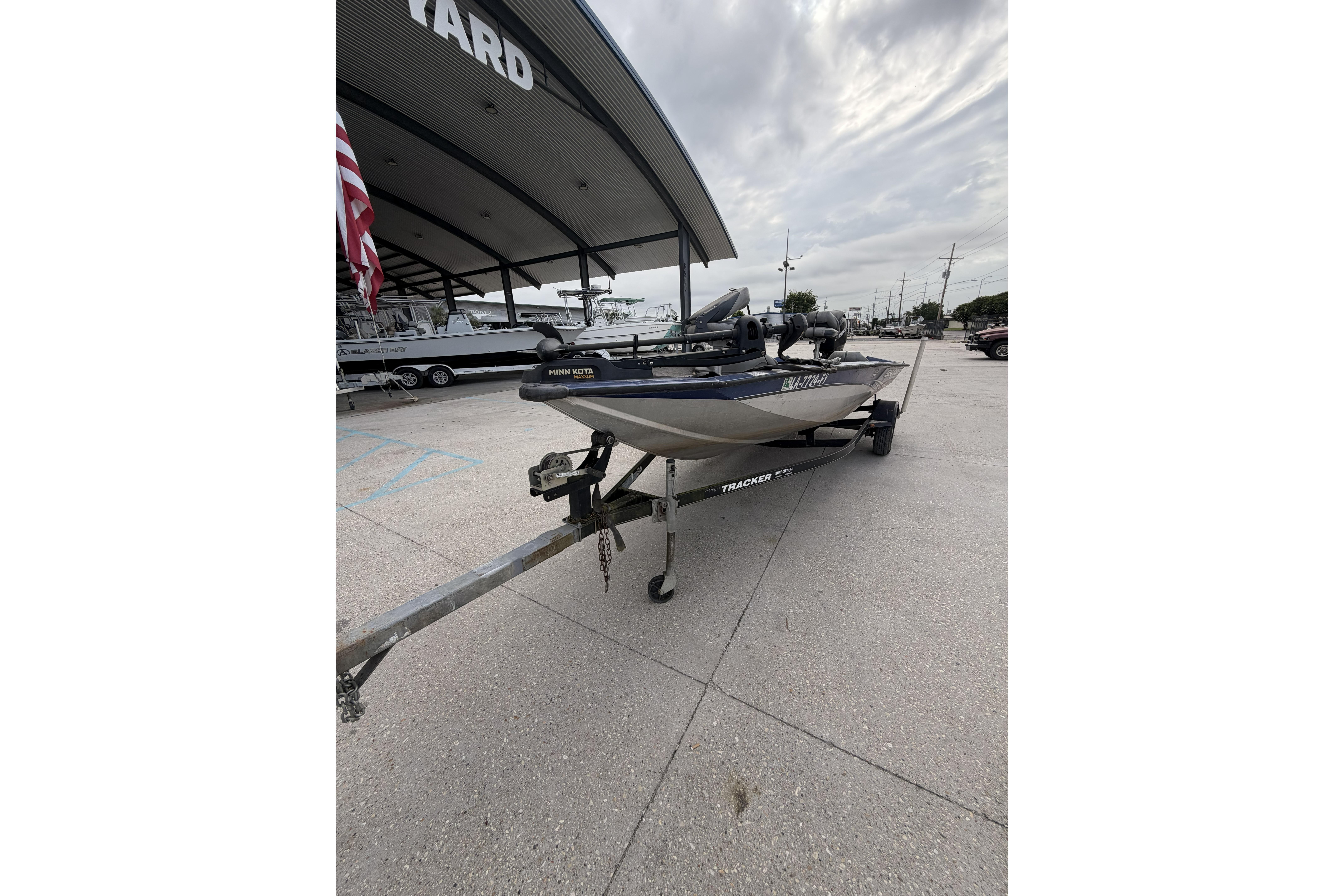 2012 Bass Tracker Pro 17 boat on trailer at a dealership, under cloudy skies.