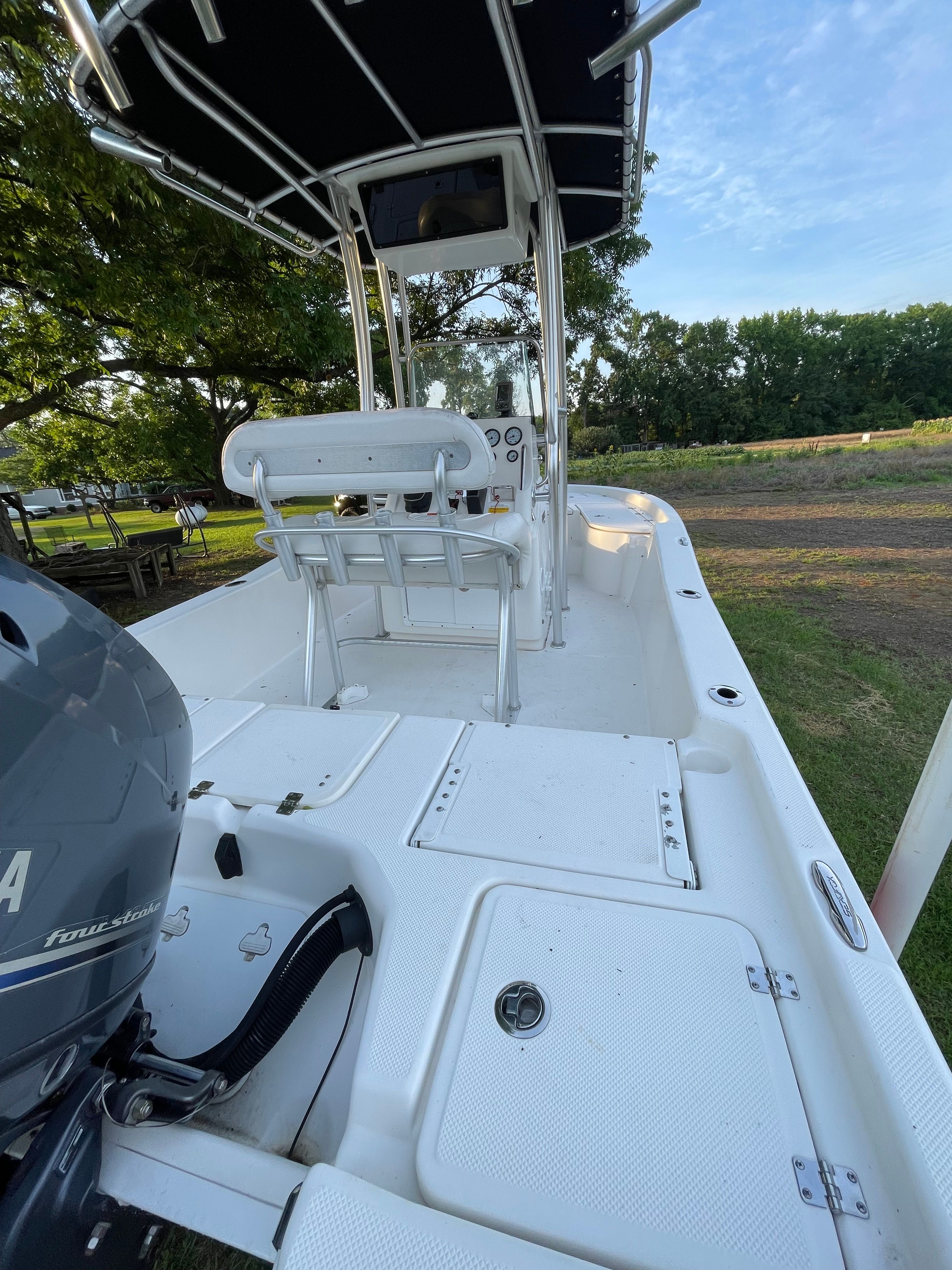 A 2012 Sea Fox 200XT boat on a trailer, surrounded by trees and grass.