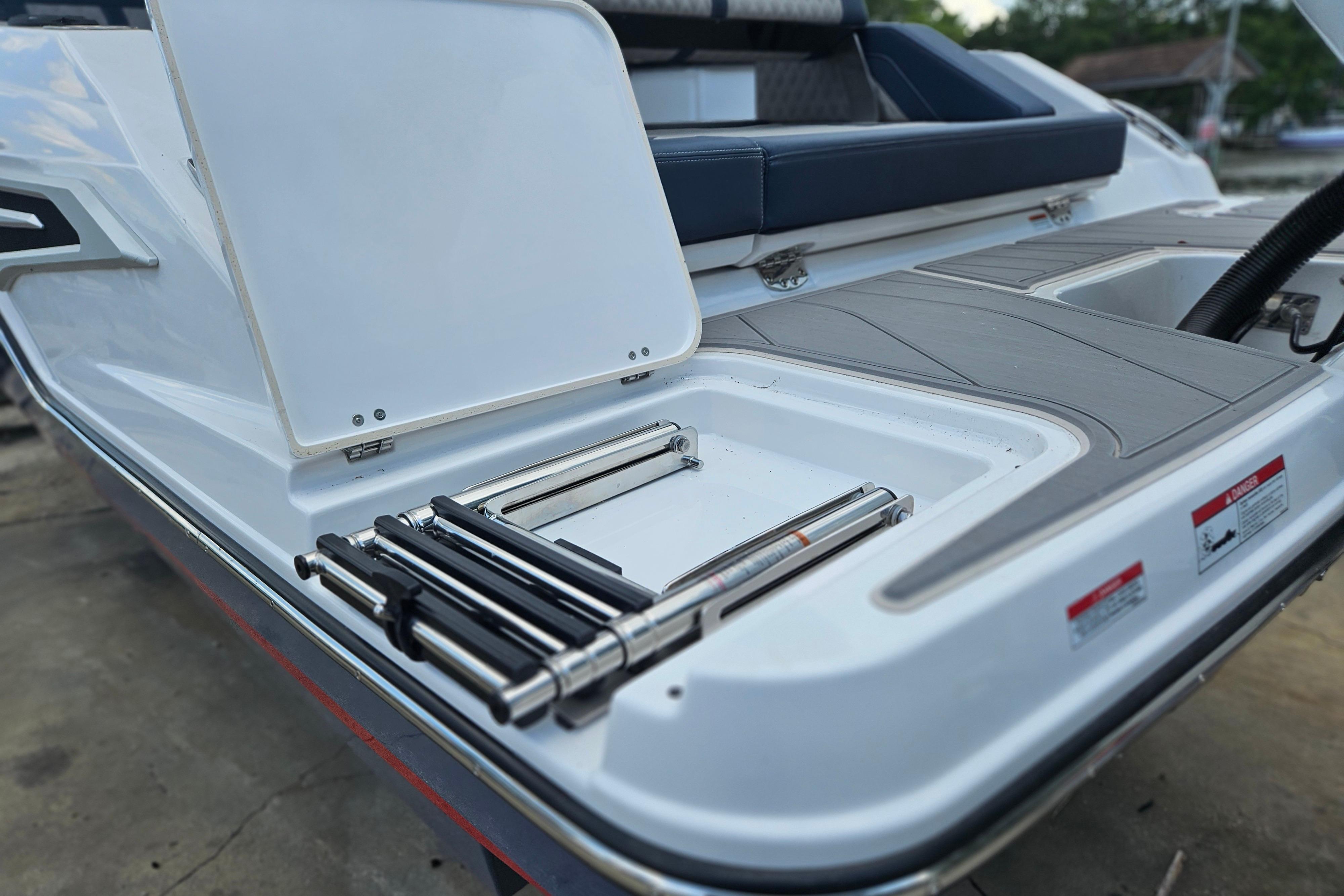 2026 Monterey Elite 27 OB boat with open storage compartment and ladder.