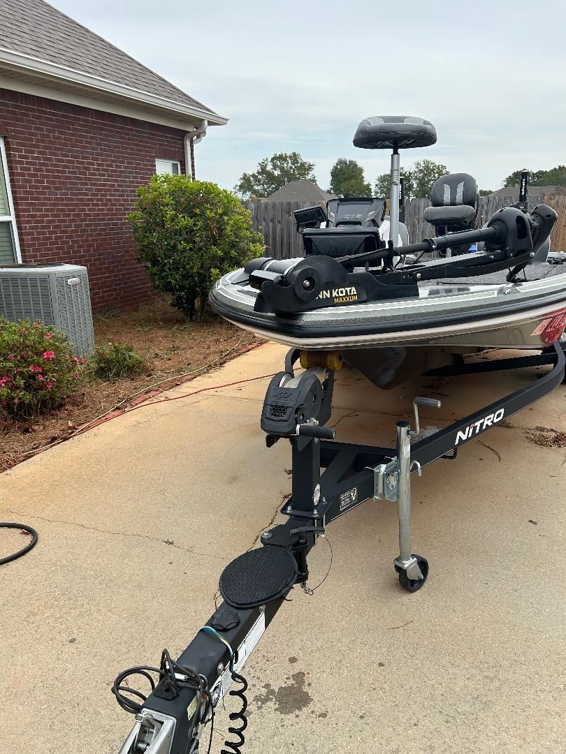 A 2020 Nitro Z18 boat on a trailer, parked on a driveway next to a brick house.