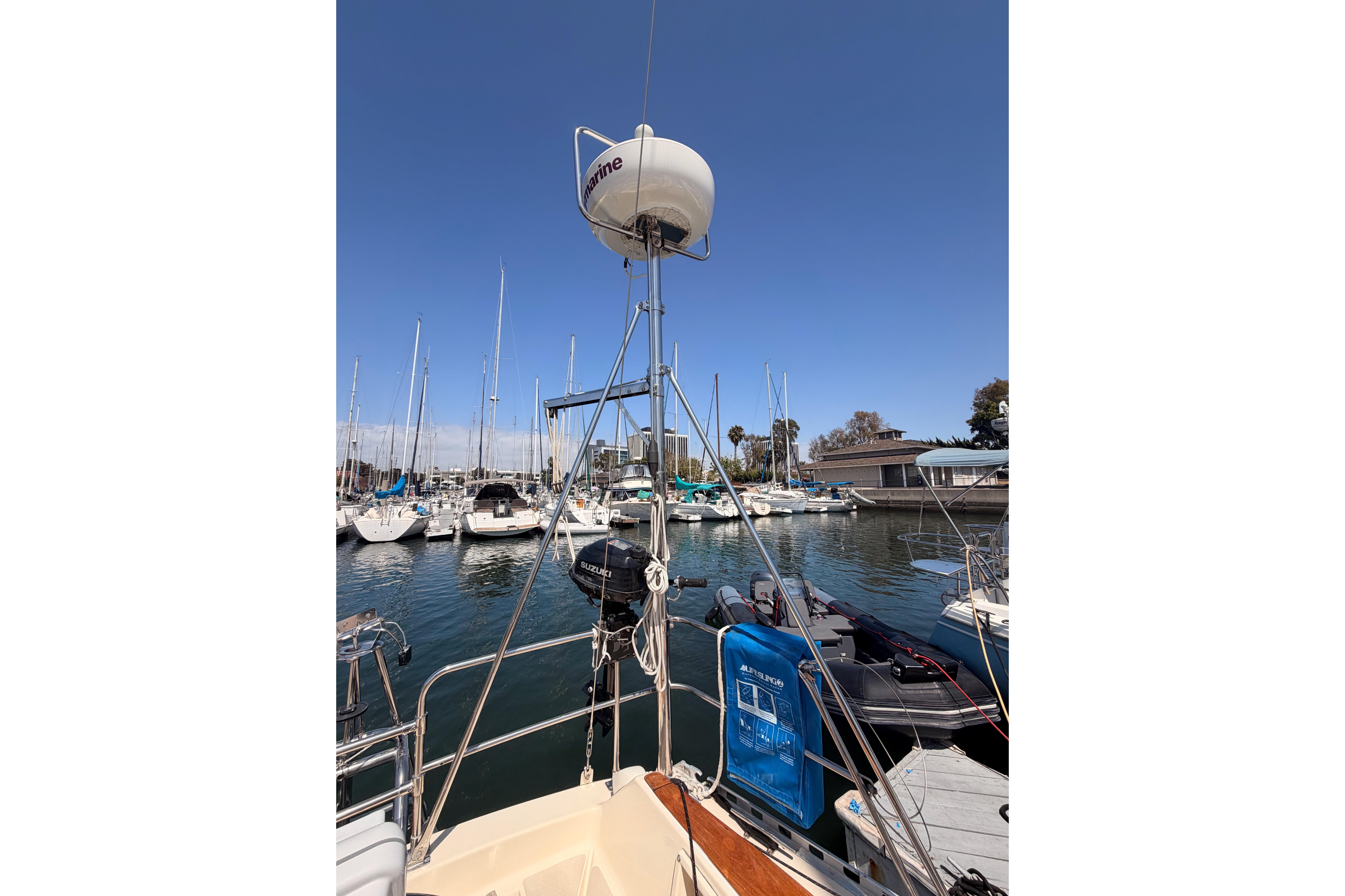 1991 Caliber 33 sailboat docked in a marina, surrounded by other boats under a clear blue sky.