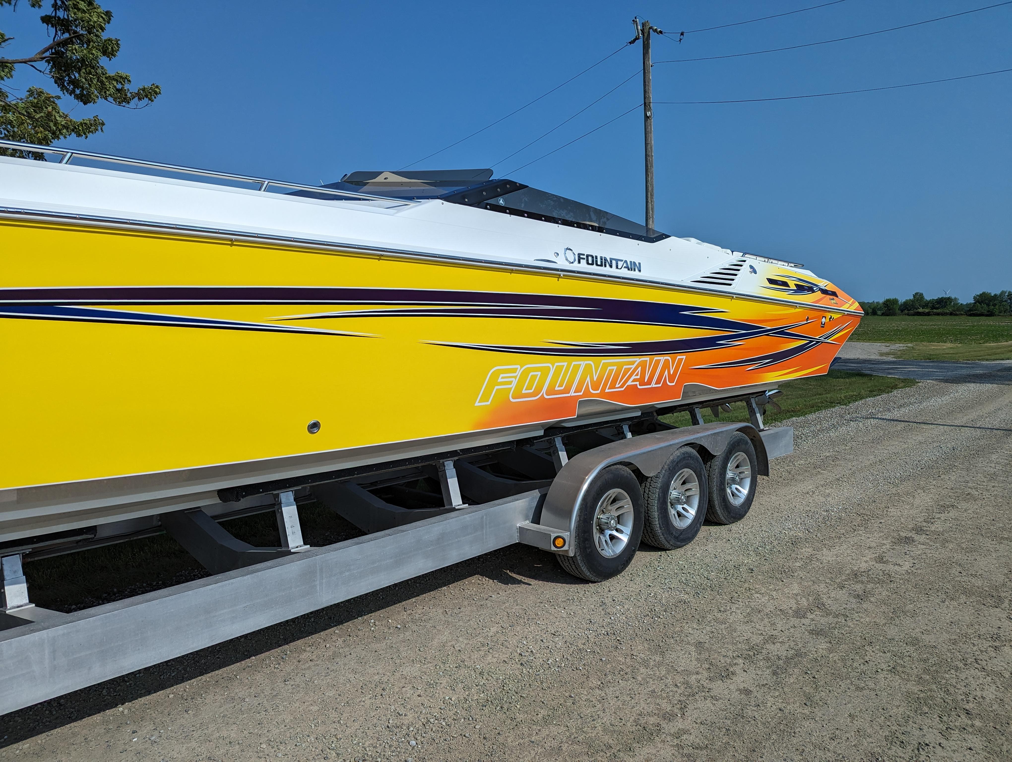 2006 Fountain 42 speedboat with vibrant yellow and orange design on a trailer.