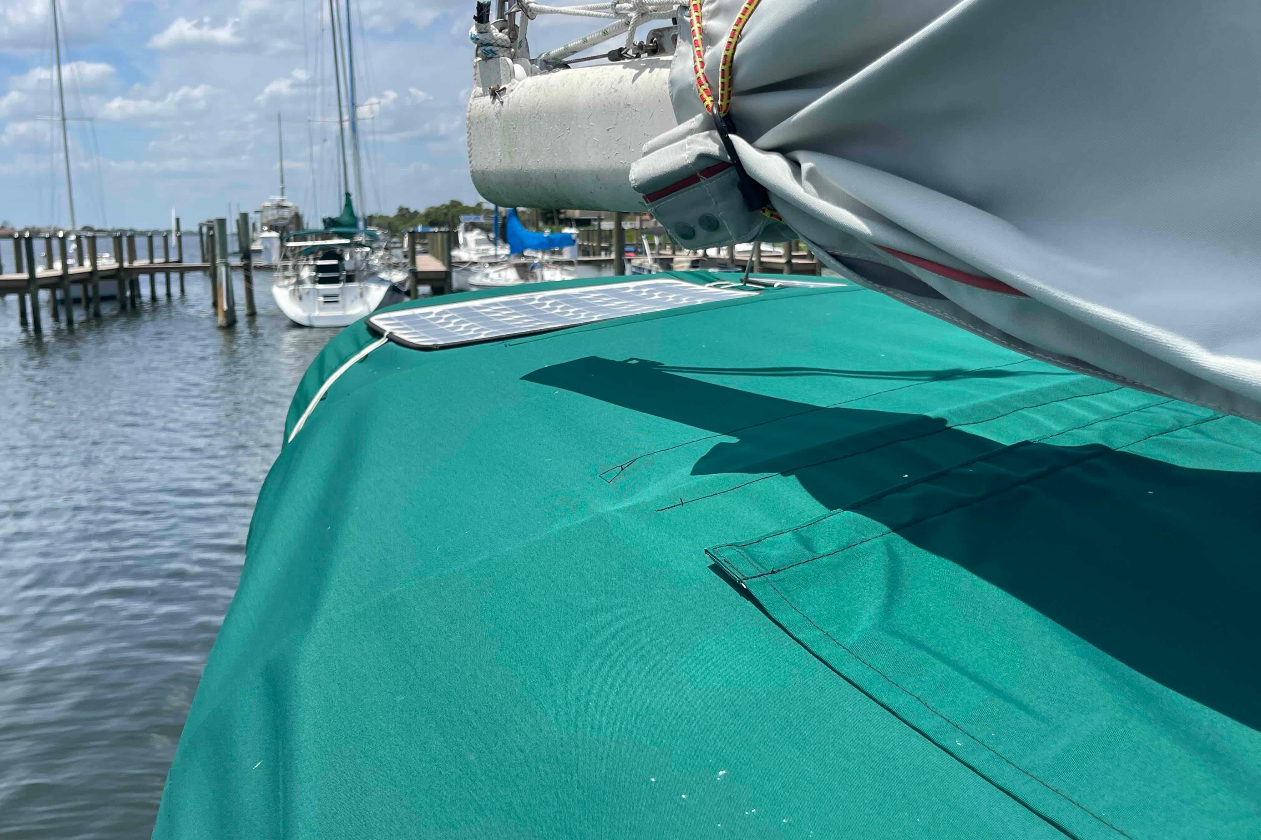 1987 Pacific Seacraft 34 sailboat docked, featuring green deck cover and folded sail.