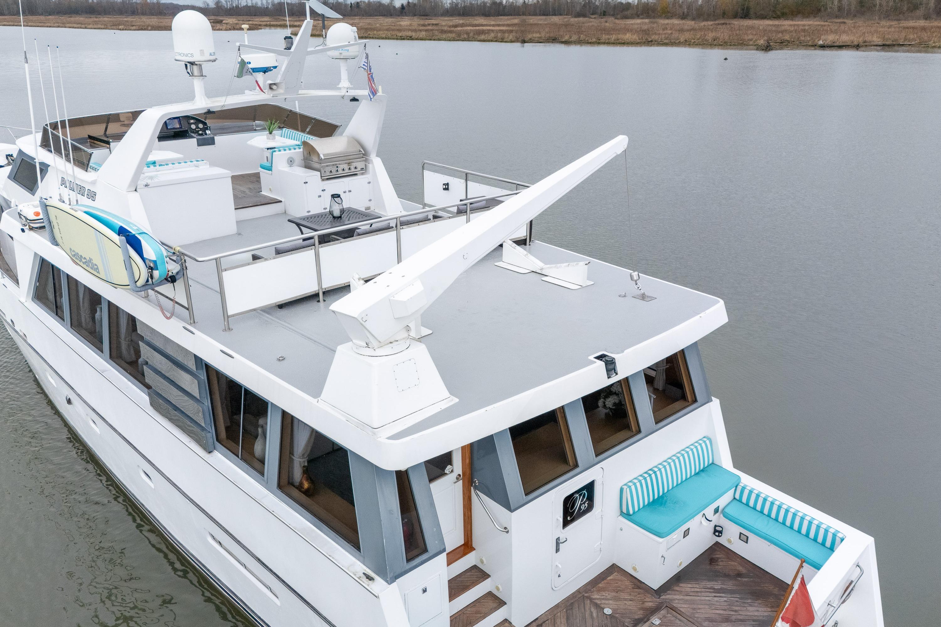 1989 Palmer Marine Pilothouse Motor Yacht on calm water, featuring deck seating and surfboards.