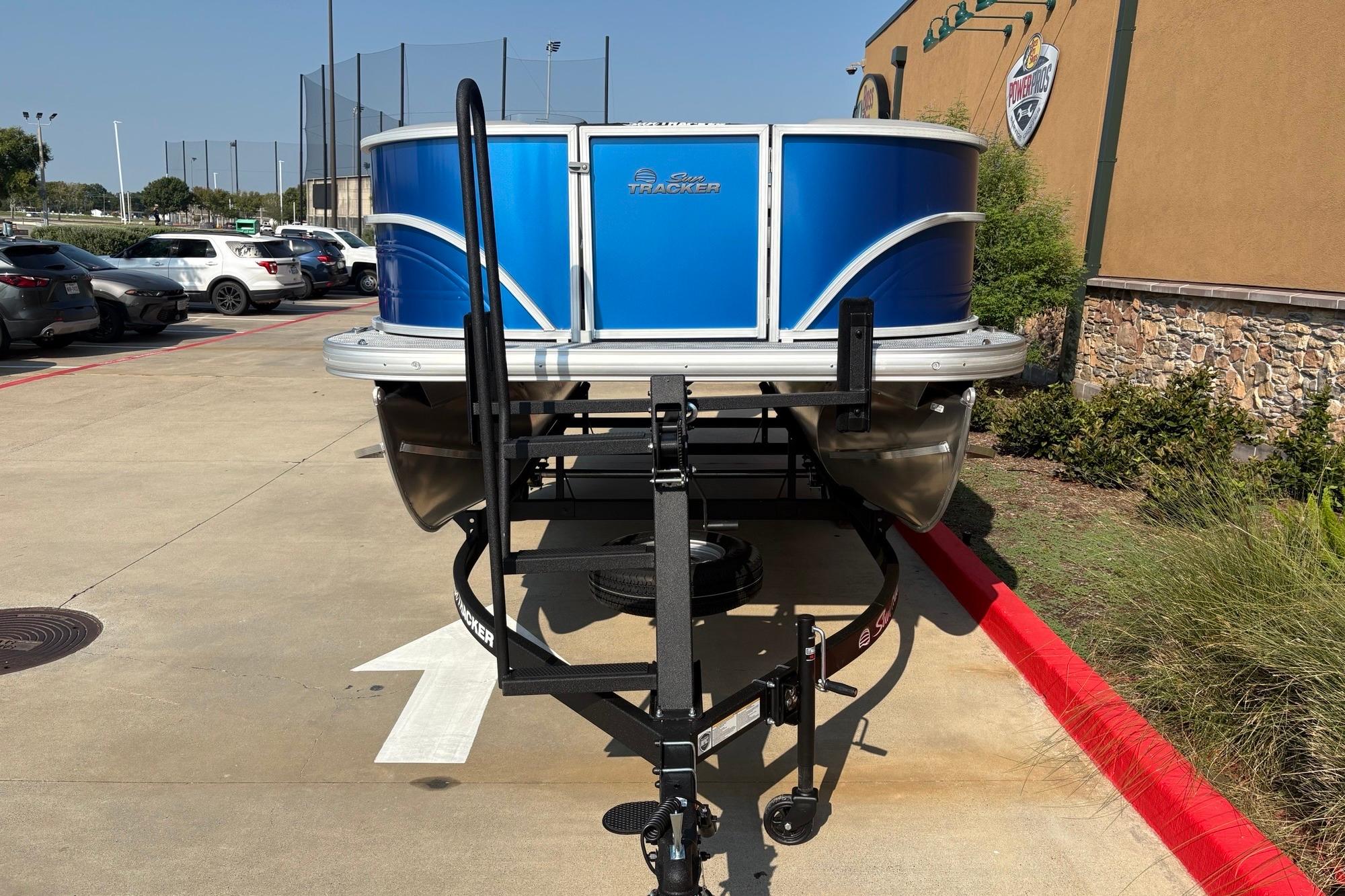 2026 Sun Tracker Party Barge 16 DLX pontoon boat on trailer in parking lot.