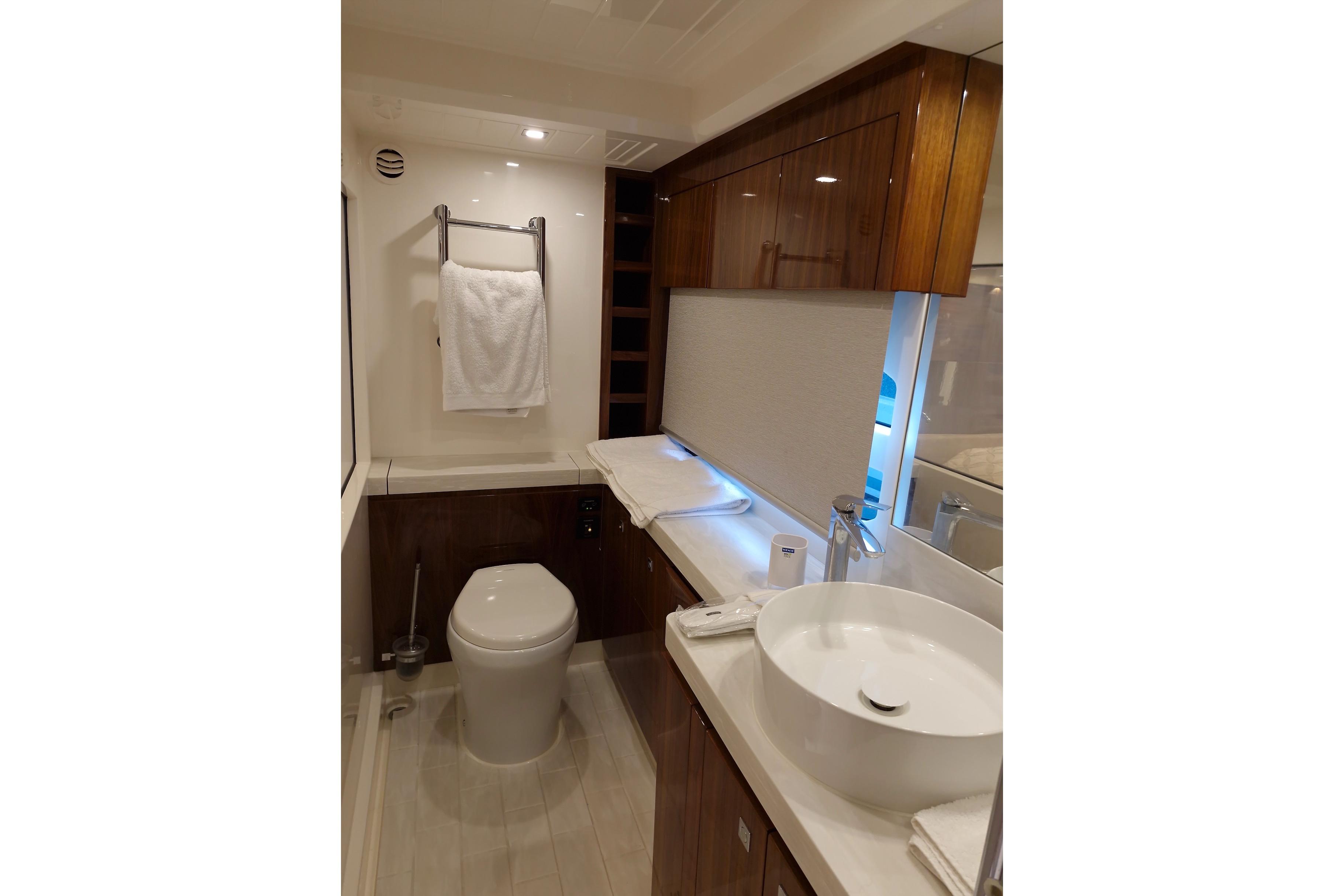 Luxurious bathroom in 2020 Riviera 6000 Sport Yacht Platinum Edition, featuring modern fixtures and elegant wood cabinetry.