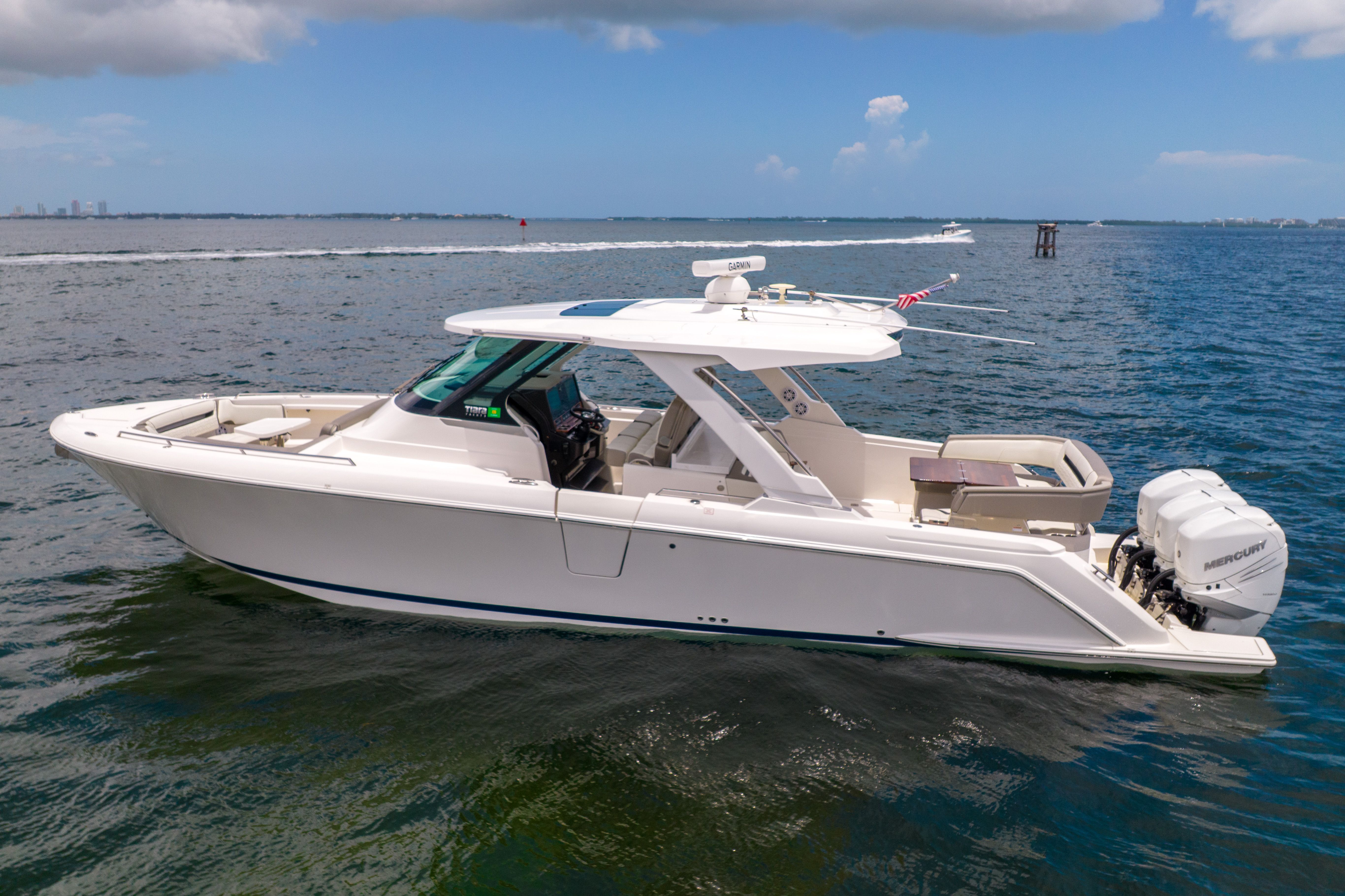 A sleek, modern motorboat on calm water with a spacious deck and two outboard engines.