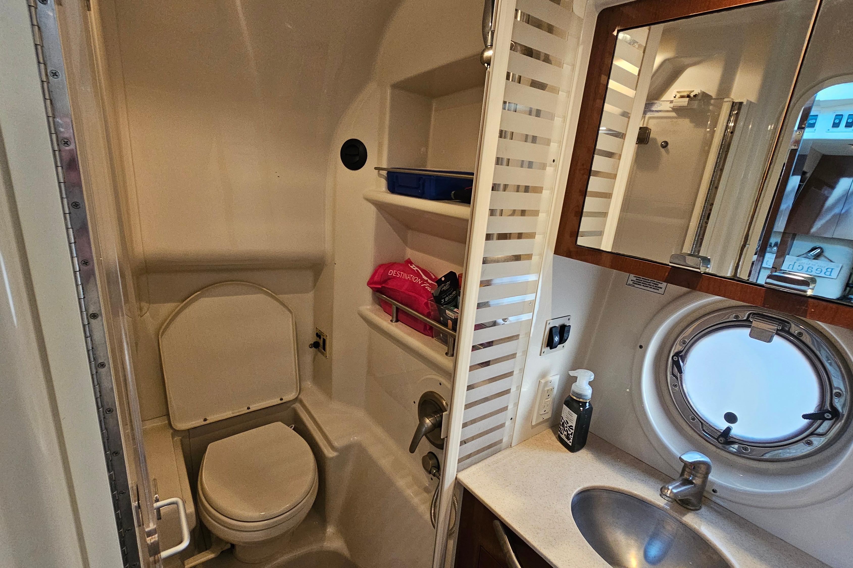 Bathroom interior of 2008 Sea Ray Sundancer 350 yacht with toilet, sink, and porthole window.