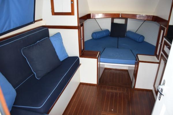 1976 Bertram Flybridge Cruiser interior with blue seating and wooden accents.