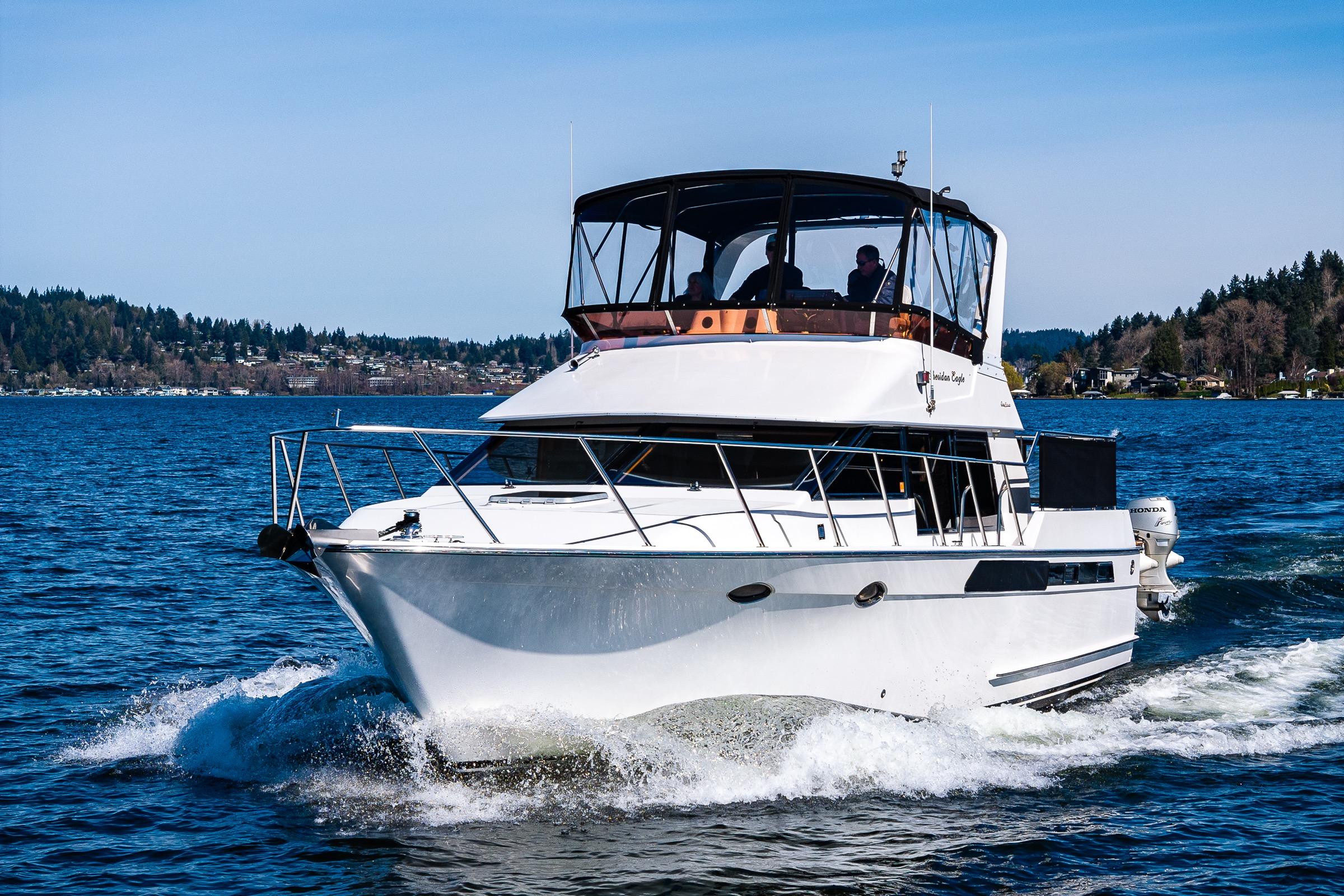 1989 Ocean Alexander 42 yacht cruising on a scenic lake with forested shoreline.