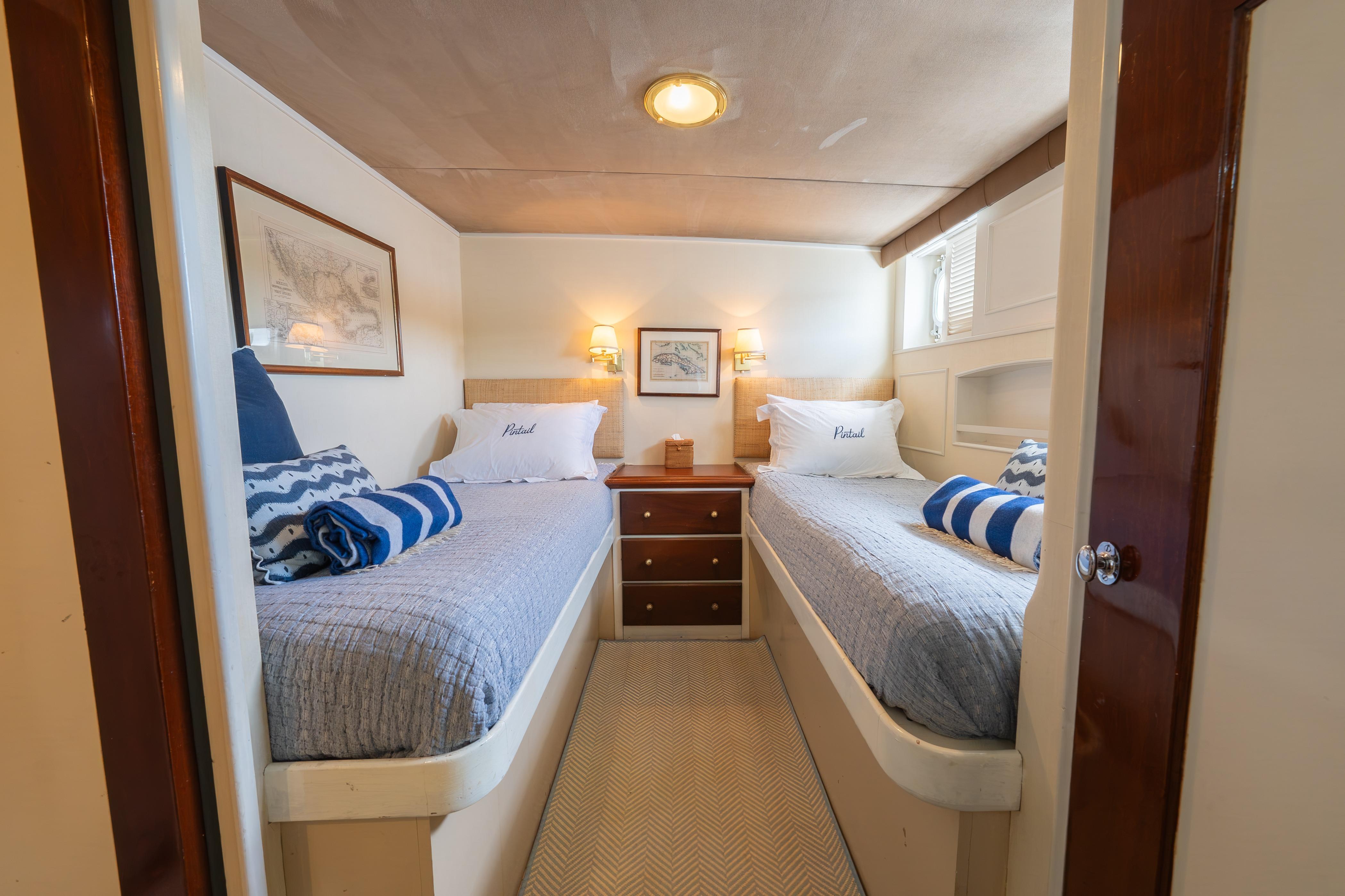 Twin beds in a cozy 1963 Trumpy Classic yacht cabin with nautical decor.