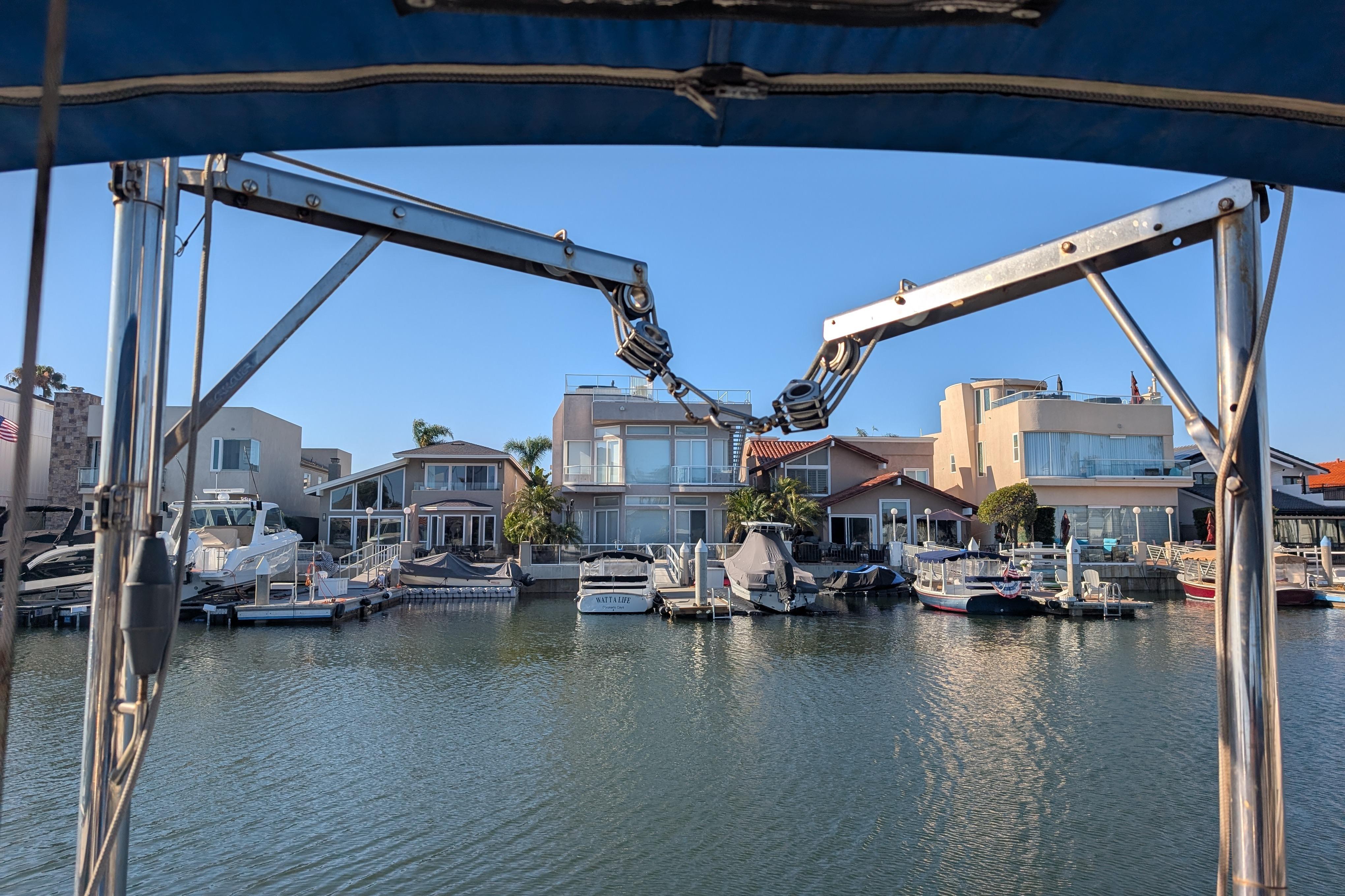 View from a 1989 Catalina 34 sailboat, overlooking waterfront homes and docked boats.