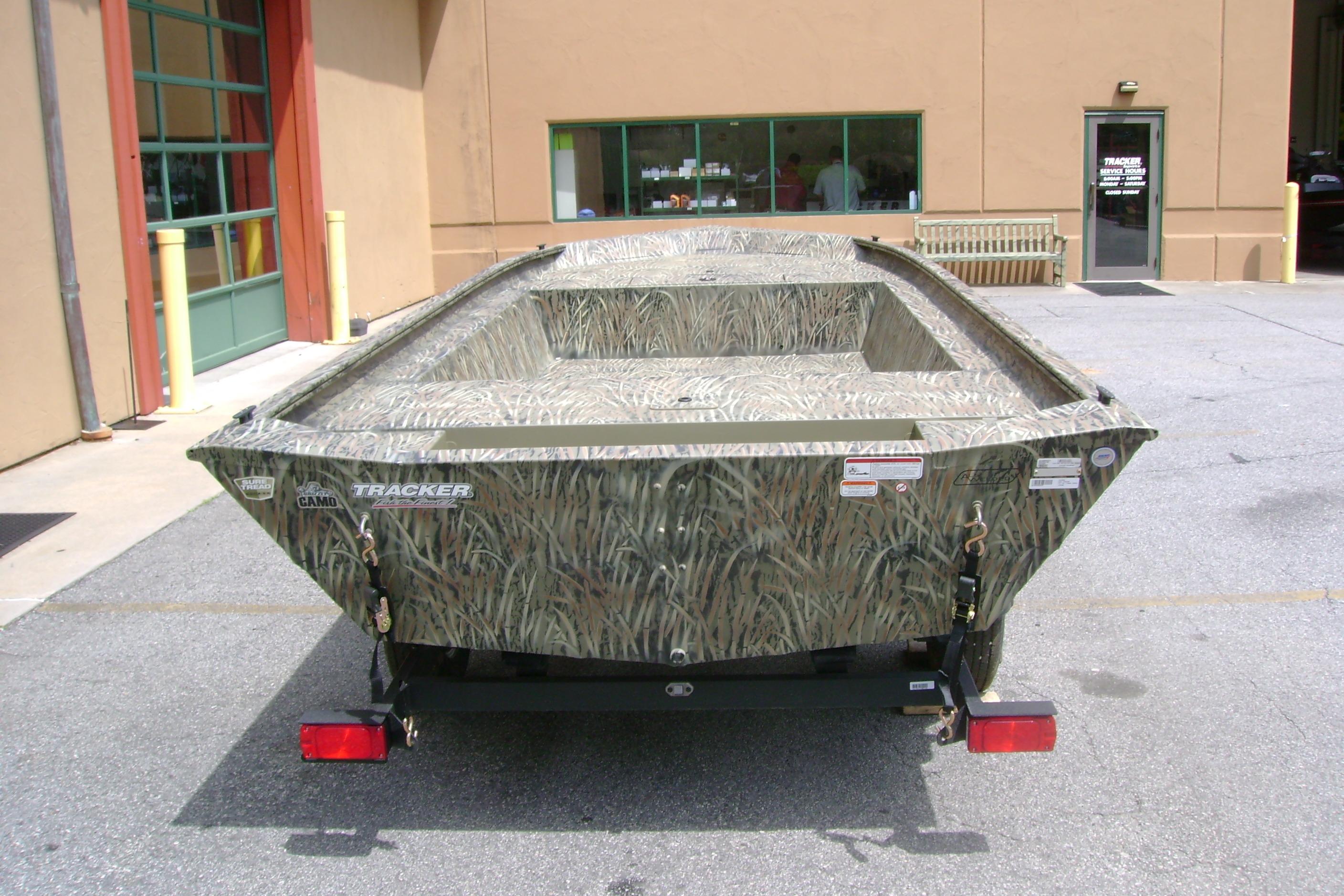 2026 Tracker Grizzly 1754 Utility boat with camouflage design parked outside a building.
