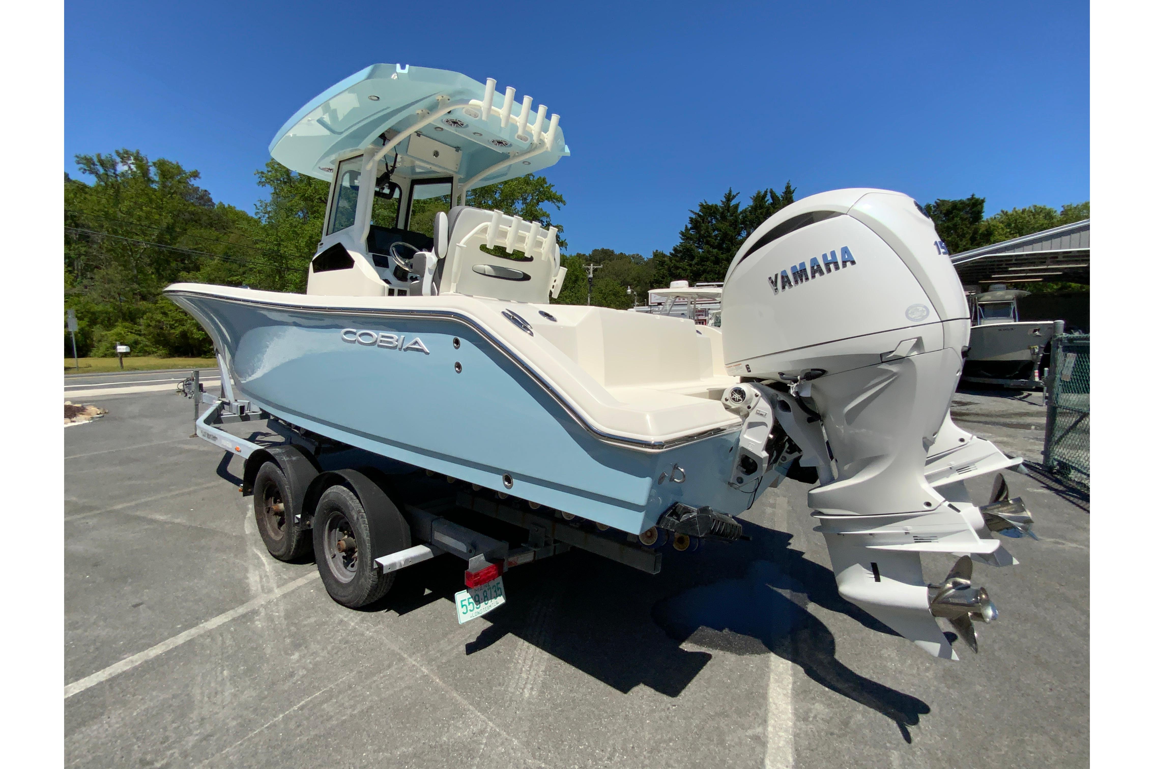 2026 Cobia 245 Center Console boat with Yamaha engine on a trailer, parked outdoors.