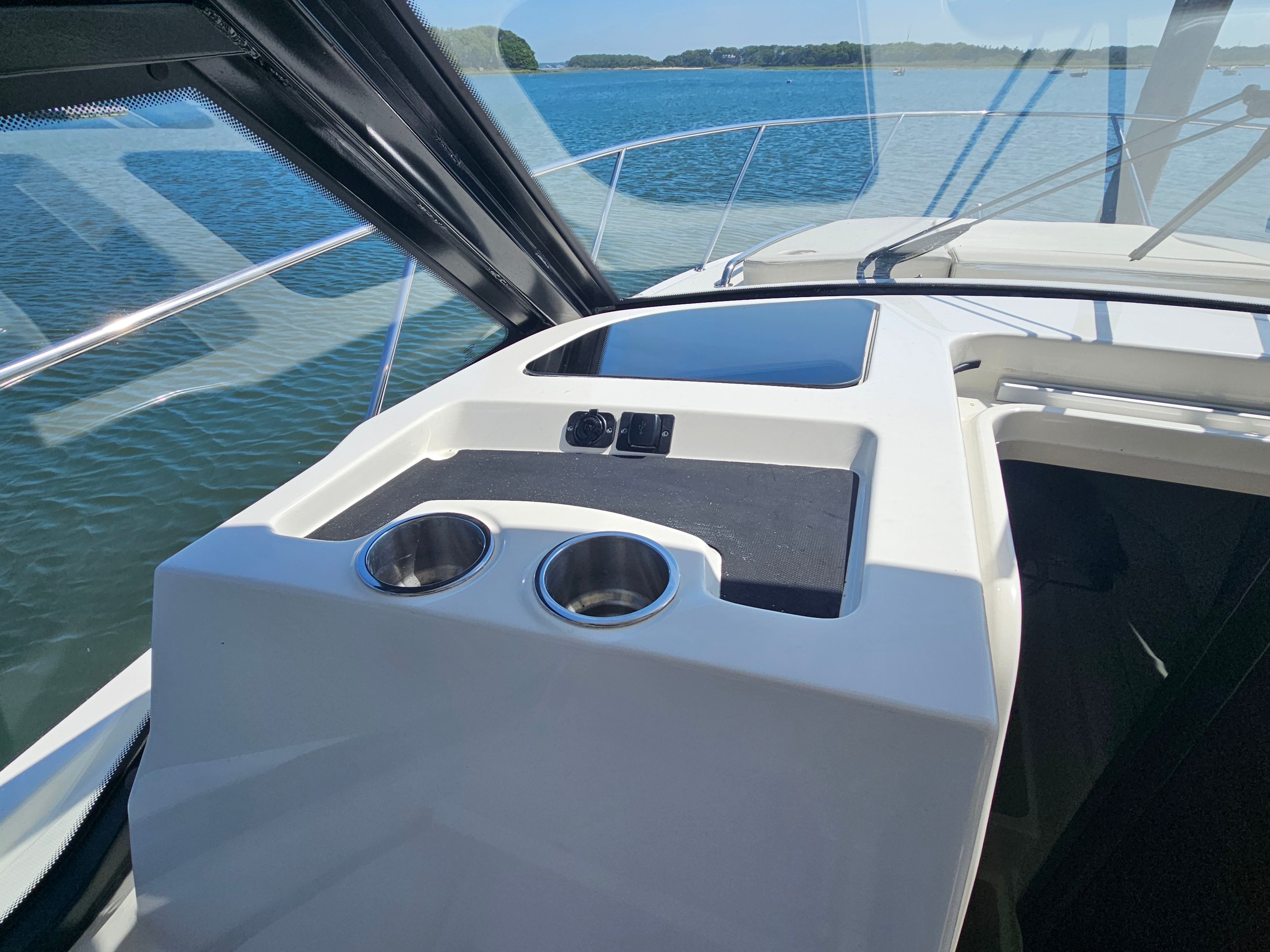 The cockpit of the Boston Whaler 325 Conquest features cup holders and a modern dashboard.
