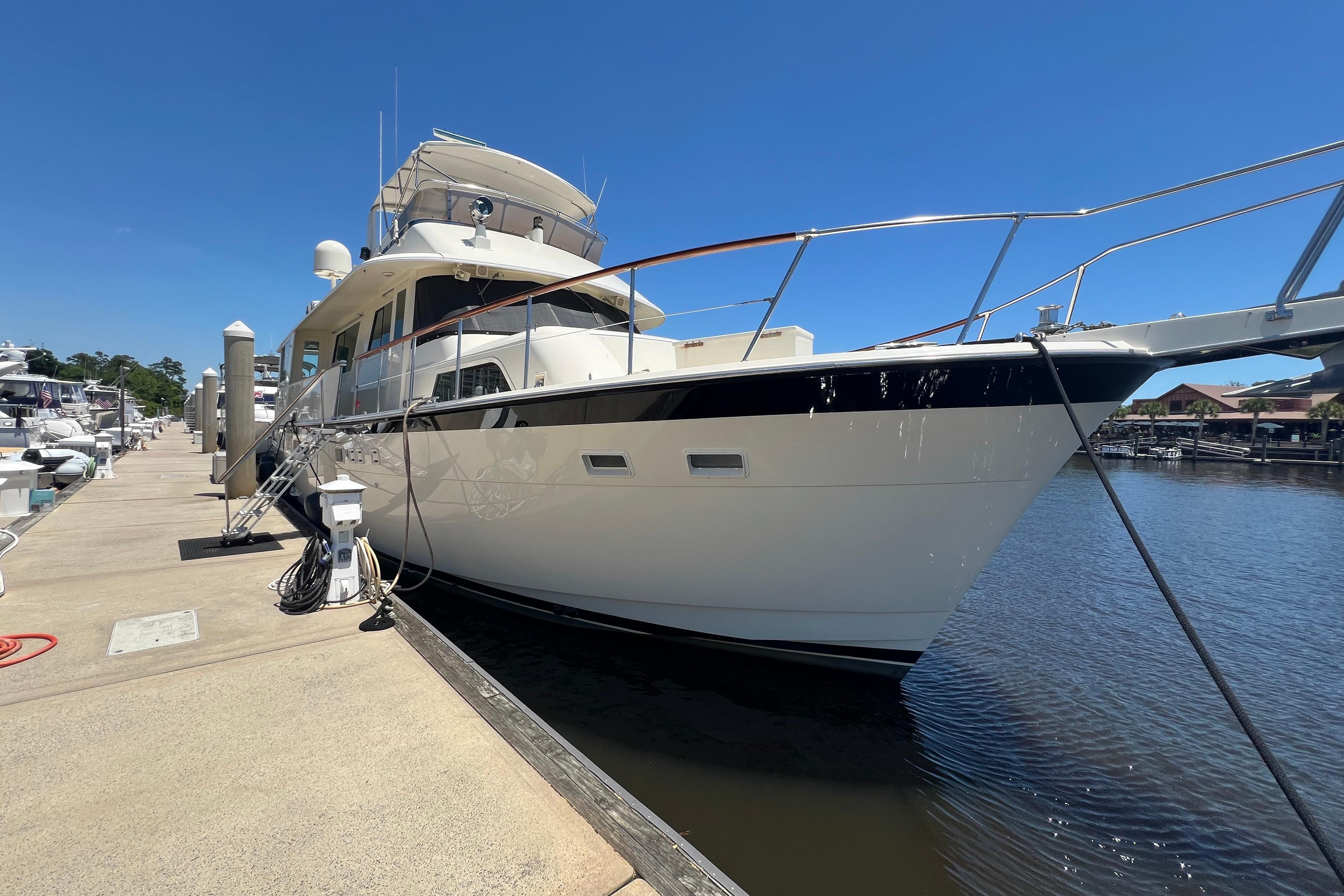 1987 Hatteras 70 Cockpit Motor Yacht docked at marina under clear blue sky.