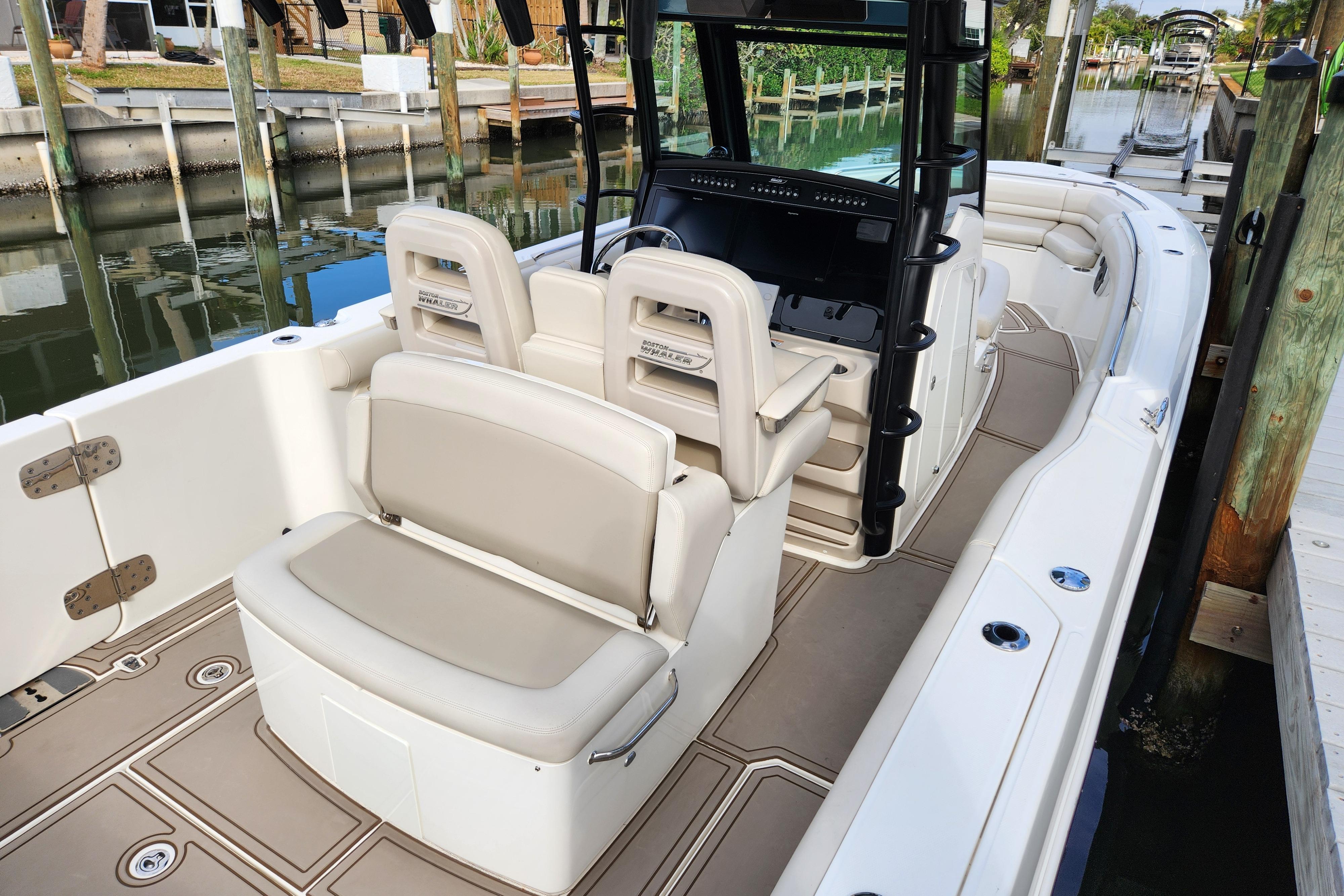 2022 Boston Whaler 330 Outrage boat interior with seating and helm, docked by the water.