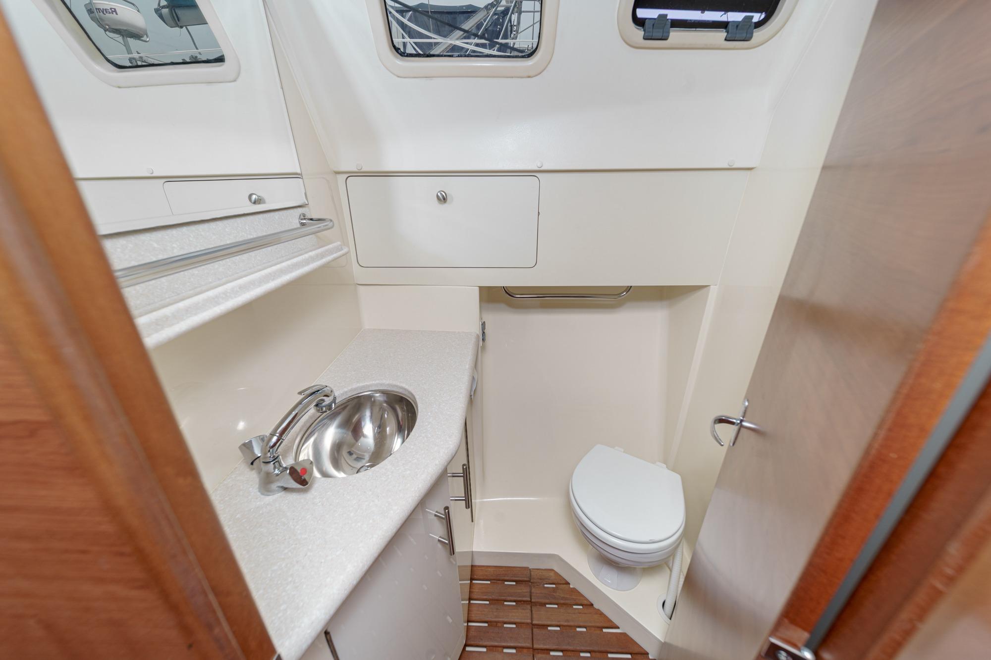 Compact bathroom in a 2015 Hunter 33 yacht, featuring a sink, toilet, and storage.