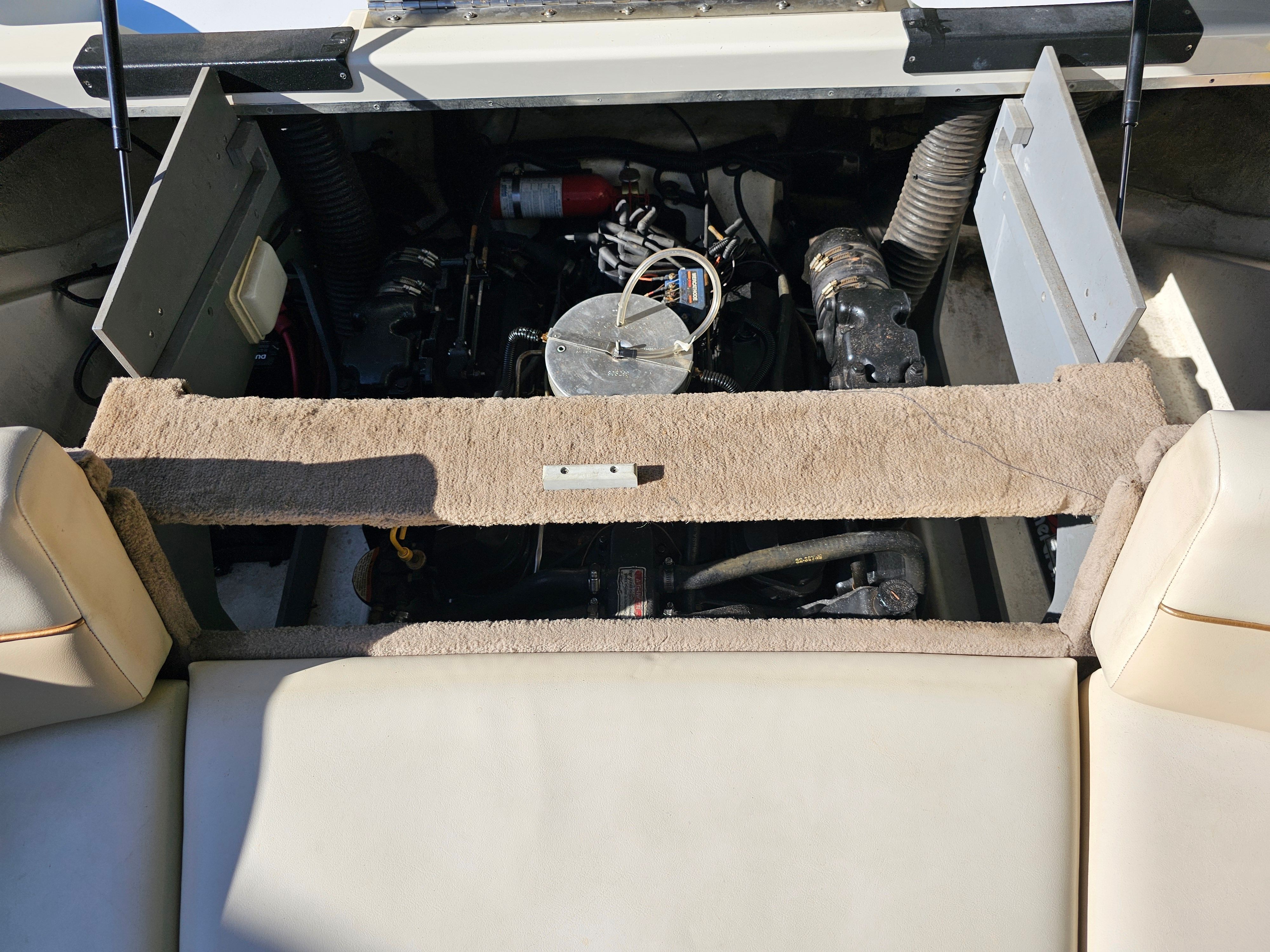 An open engine compartment of a boat with visible engine and hoses.