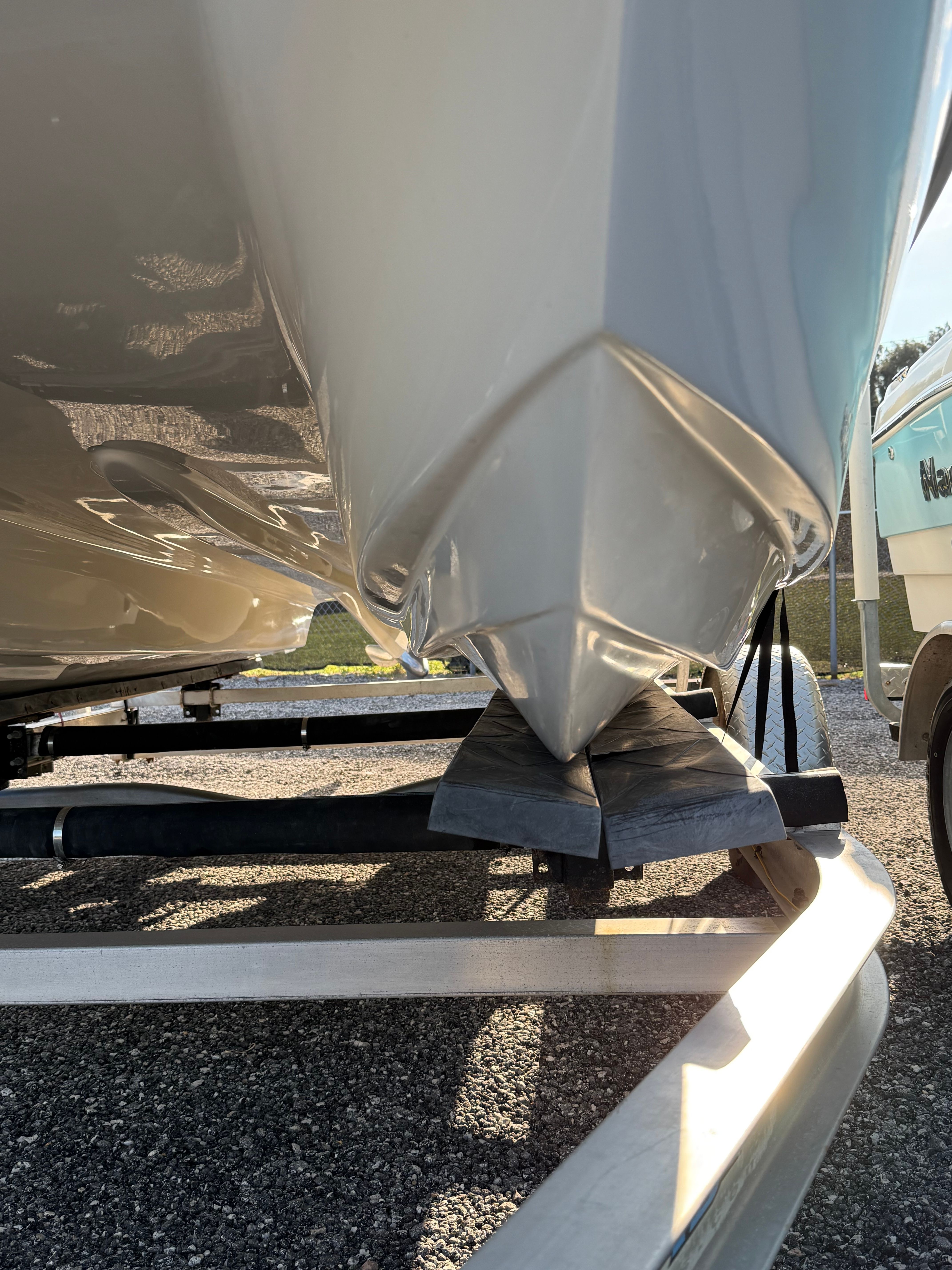 Close-up of a boat hull on a trailer, with sunlight and shadows.