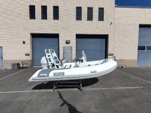 2025 Tide Craft San Juan 11 boat on trailer, parked outside industrial building.