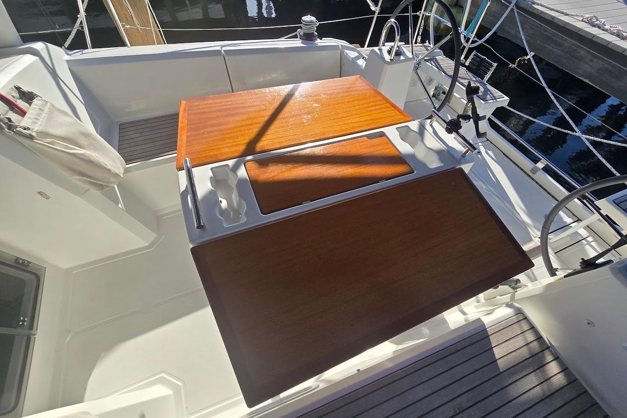 2023 Beneteau Oceanis 38.1 cockpit with wooden table and dual steering wheels.