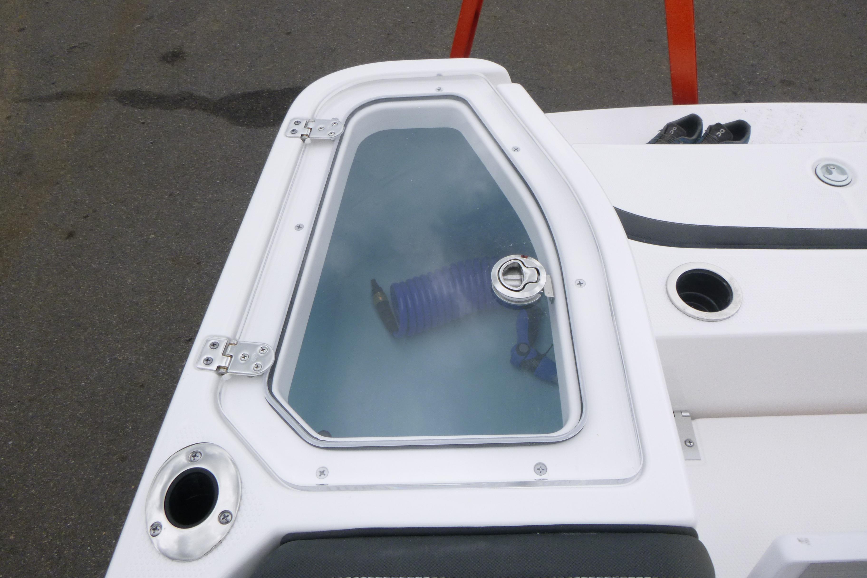 2026 Yamaha Boats 255 FSH Sport H deck with storage compartment and visible hose.