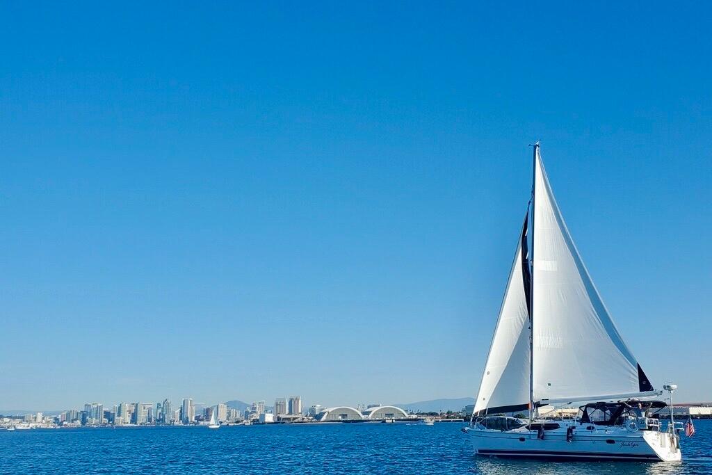 Sailing yacht Hunter 45 Deck Salon 2008 on blue ocean with city skyline backdrop.