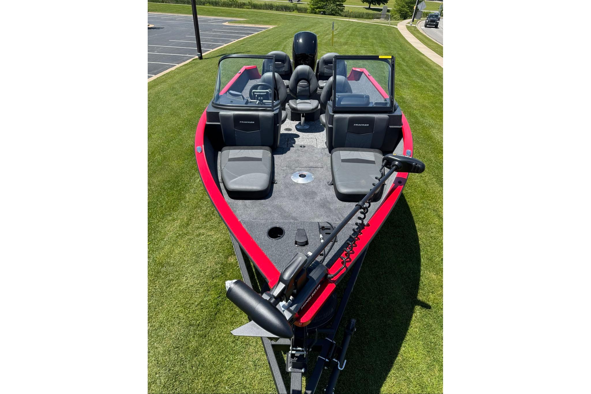 2026 Tracker Pro Guide V-16 WT boat on grass, featuring red accents and seating.
