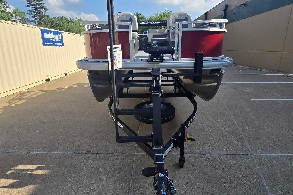 2026 Sun Tracker Bass Buggy 18 DLX pontoon boat on trailer in parking lot.